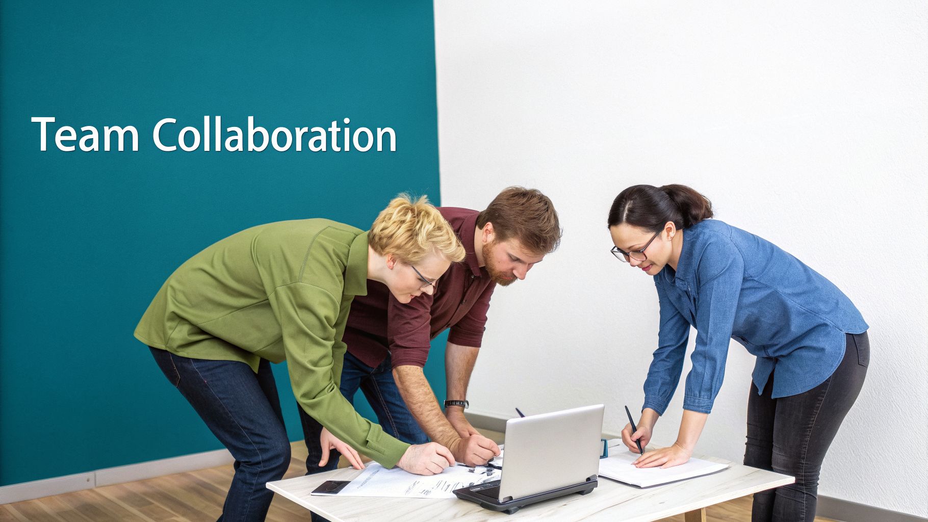 Three colleagues, two men and one woman, collaboratively working on documents around a laptop on a table.