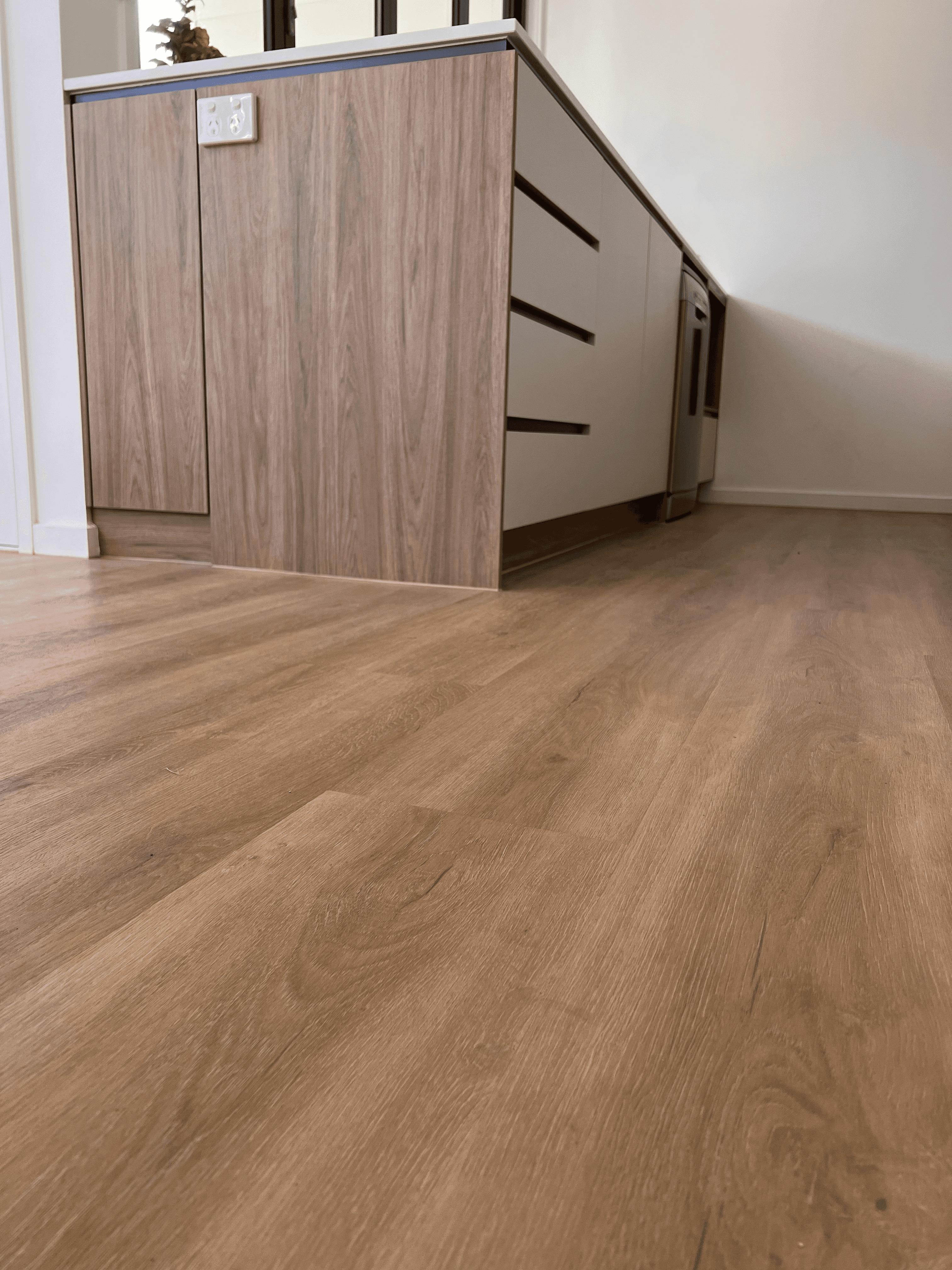 Timber-look hybrid flooring in a Queensland kitchen, built to handle spills, stains and daily foot traffic with easy maintenance.