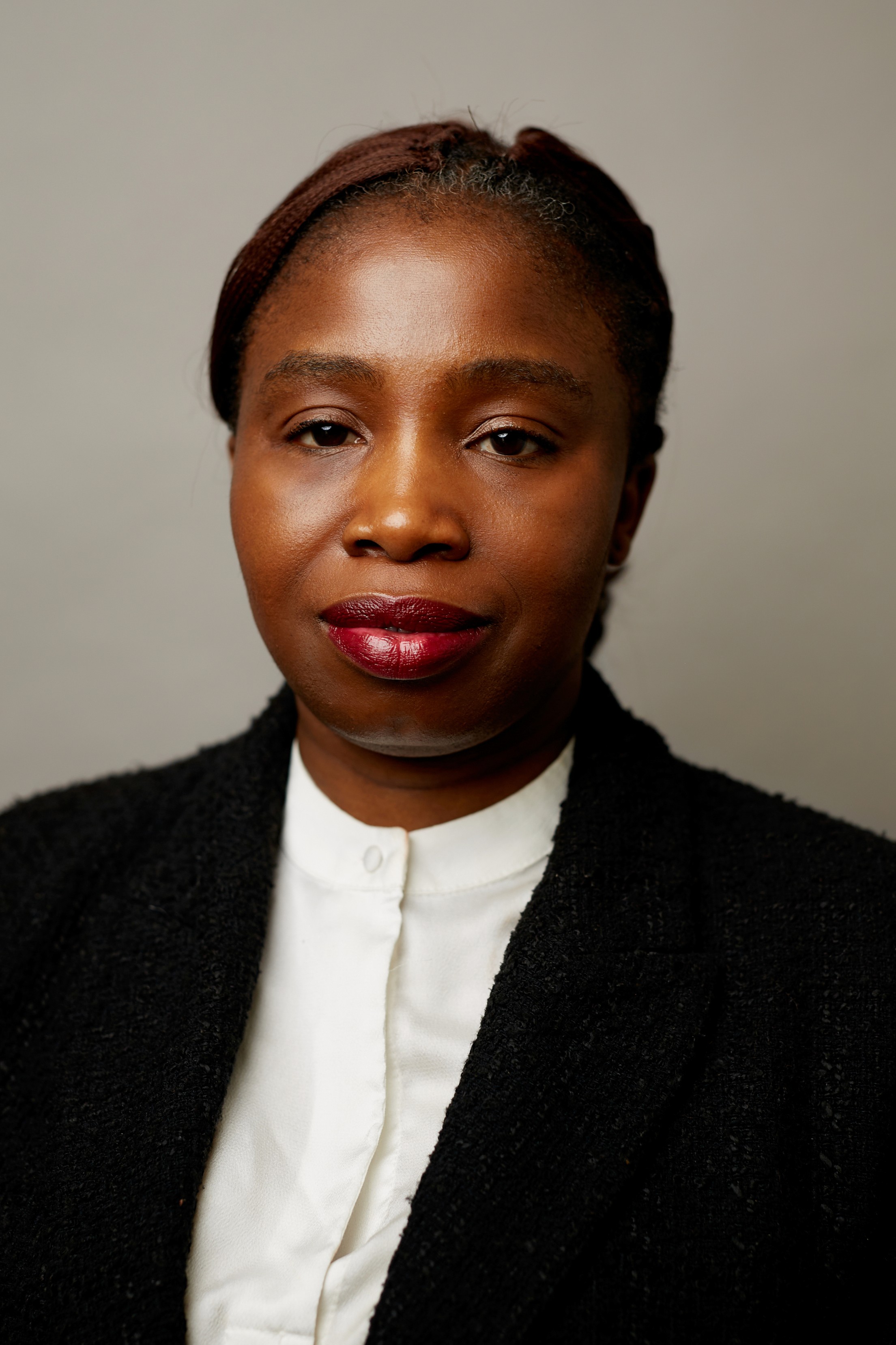 Woman in black blazer with white shirt, dark lipstick