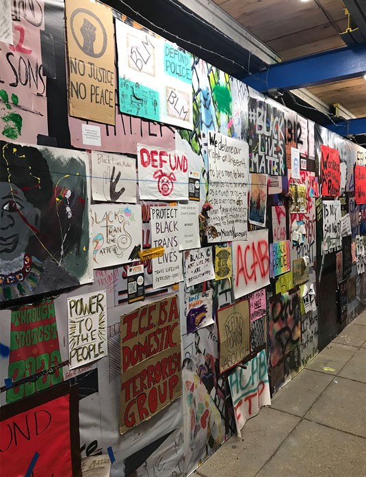 A vibrant wall covered with a variety of colorful posters and signs in a lively, urban environment.