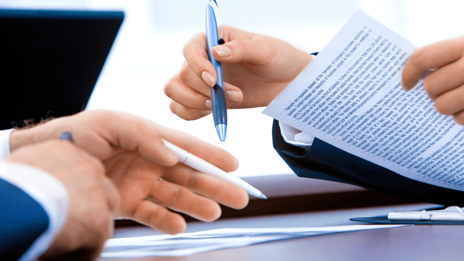 Close-up of colleagues exchanging pens over a financial report | Capel Alley