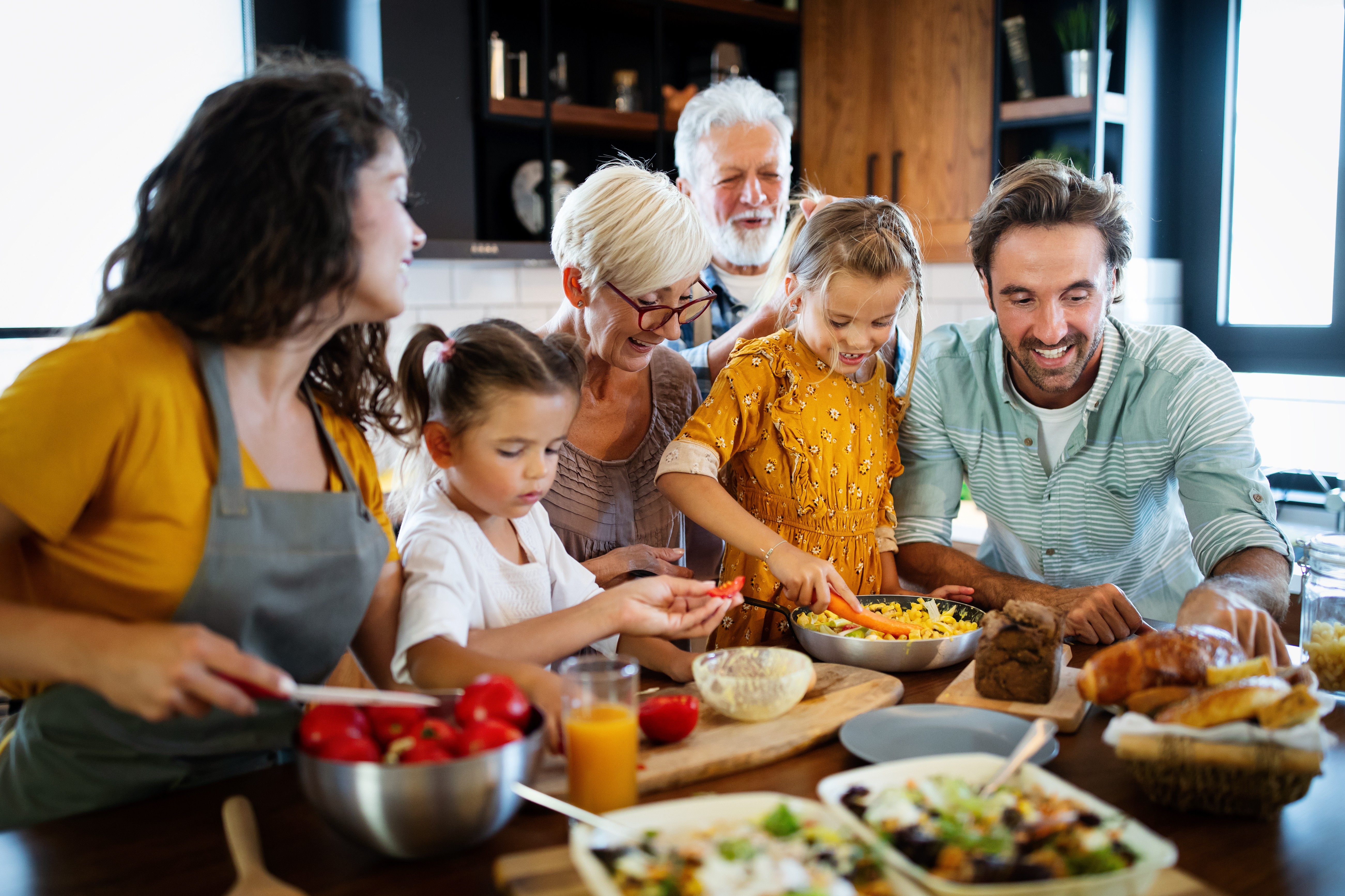 Een familie van meerdere generaties verzamelt zich in een gezellige keuken om samen een maaltijd te bereiden en te delen, glimlachend en genietend van elkaars gezelschap, waarbij de waarde van echte connectie wordt benadrukt.
