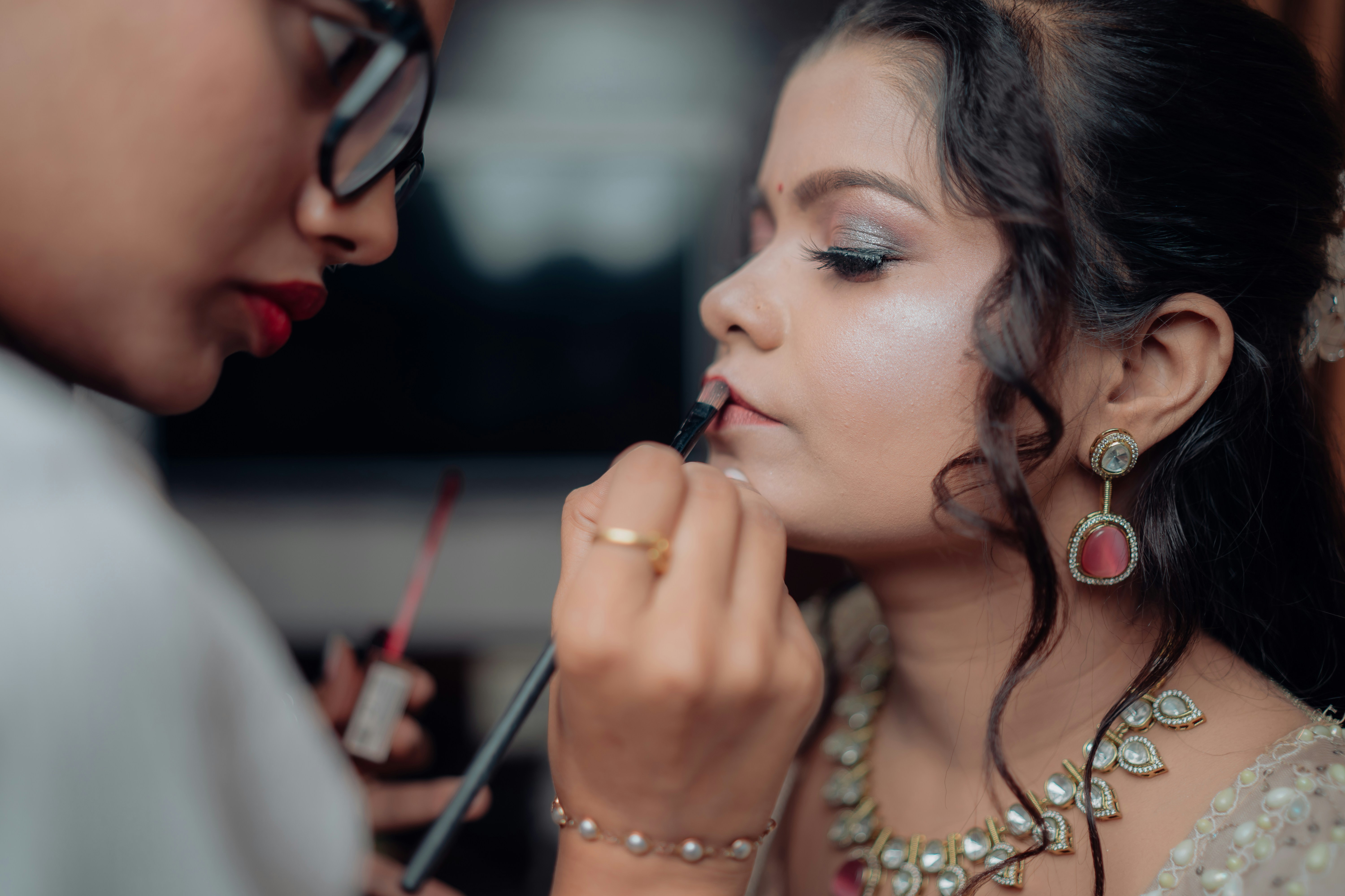 A makeup artist applies lipstick on a client.