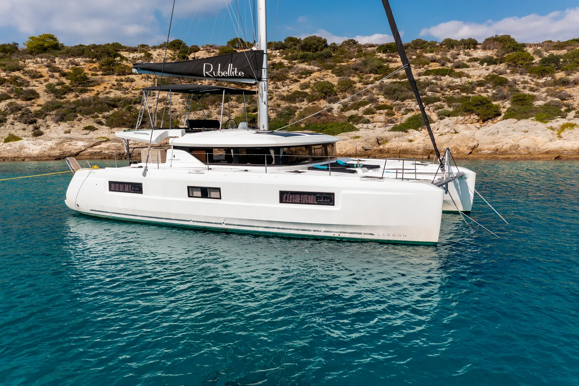 White Rock 36 speedboat with captain at helm cruising calm blue waters near Paros coastline with hills in background.