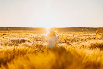 jeune fille cheveux blonds qui court dans un champ de blé au soleil