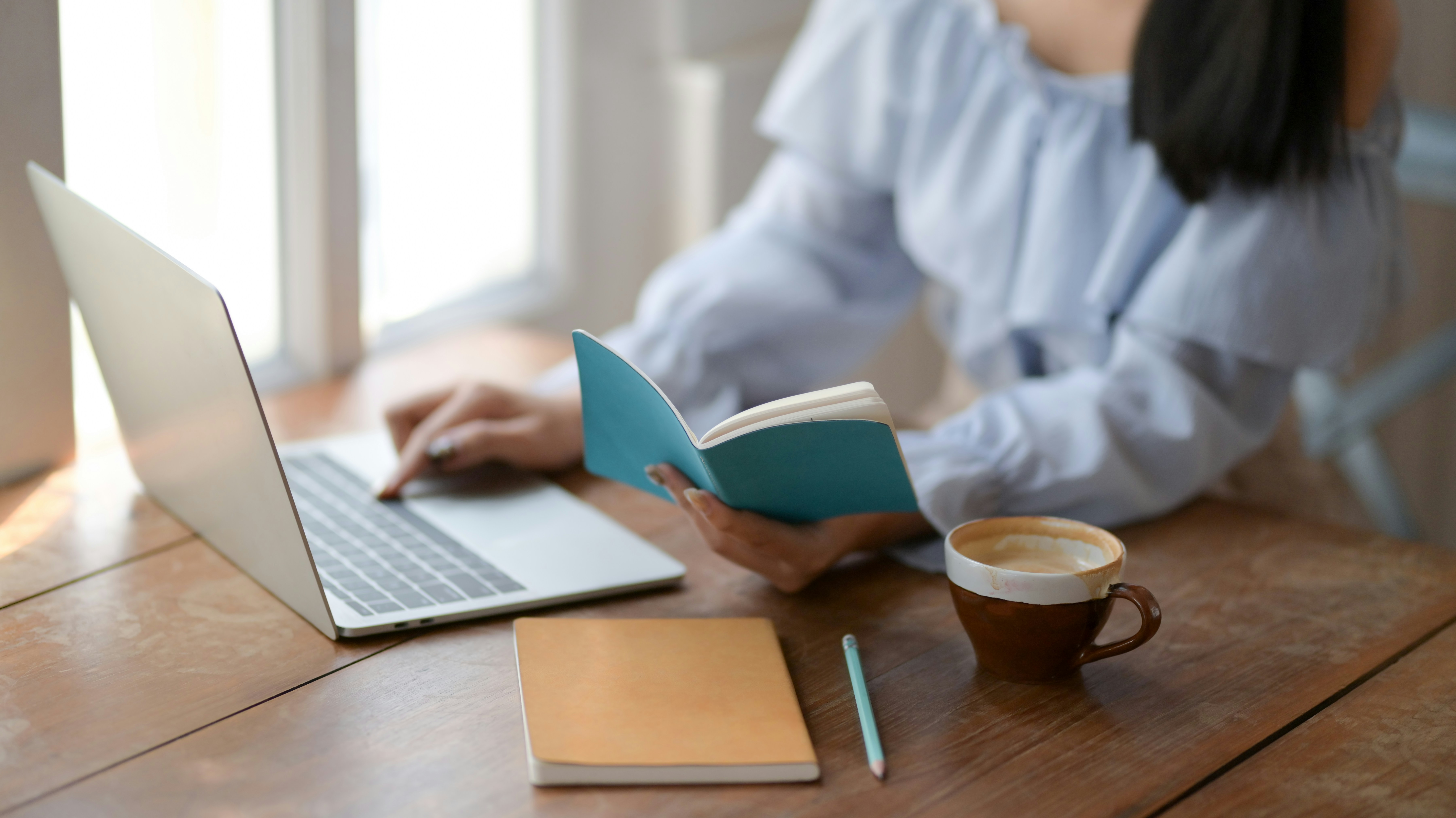 Woman working on a laptop while reviewing her resume.