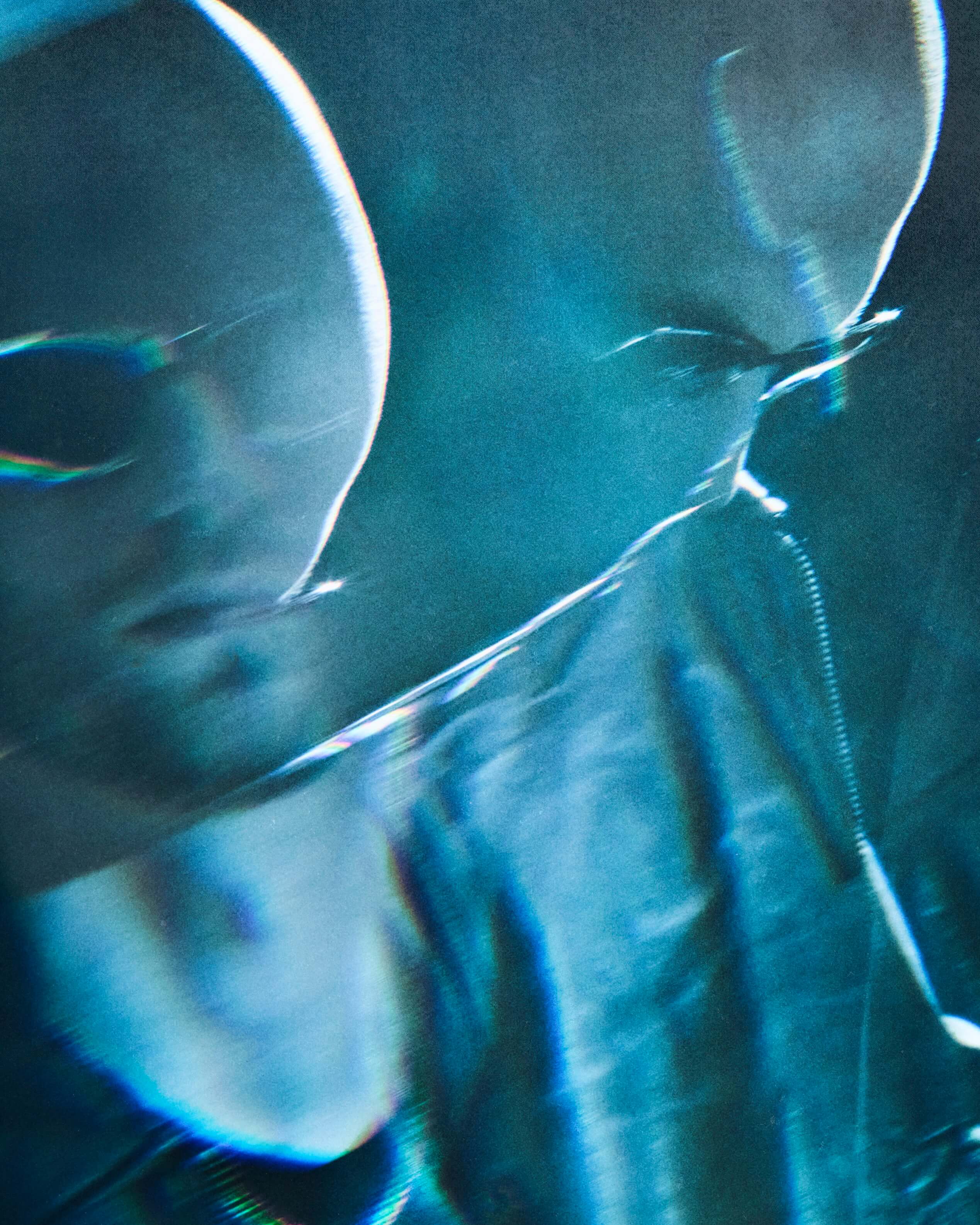 Close-up portrait of a man's face bathed in blue light with a reflective, cinematic quality