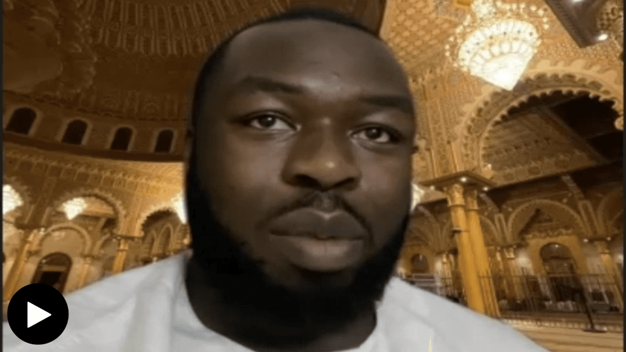Mustafa Okon-Briggs talking with a digital image in the background.