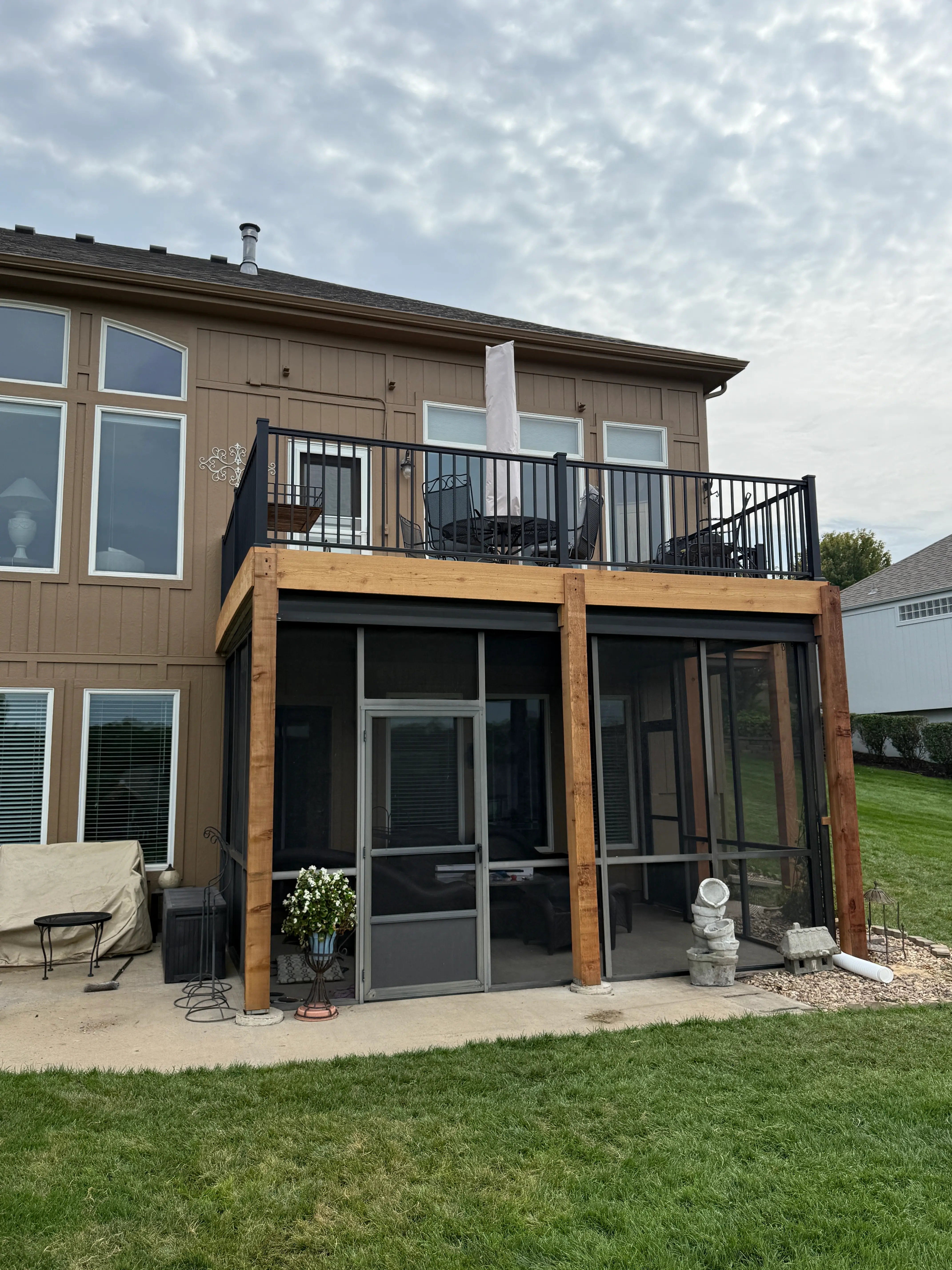 An image of deck over a screened in patio with outdoor furniture.