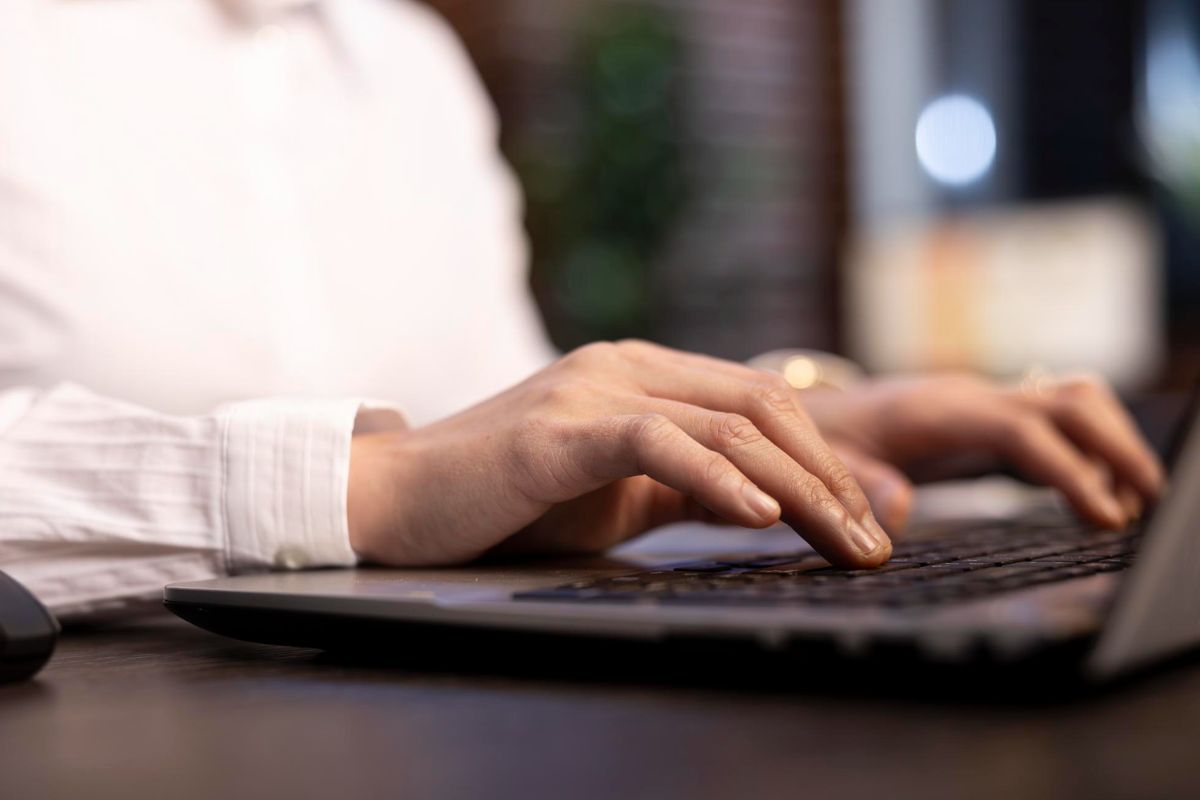 Person using a laptop while on desk with small keyboard.