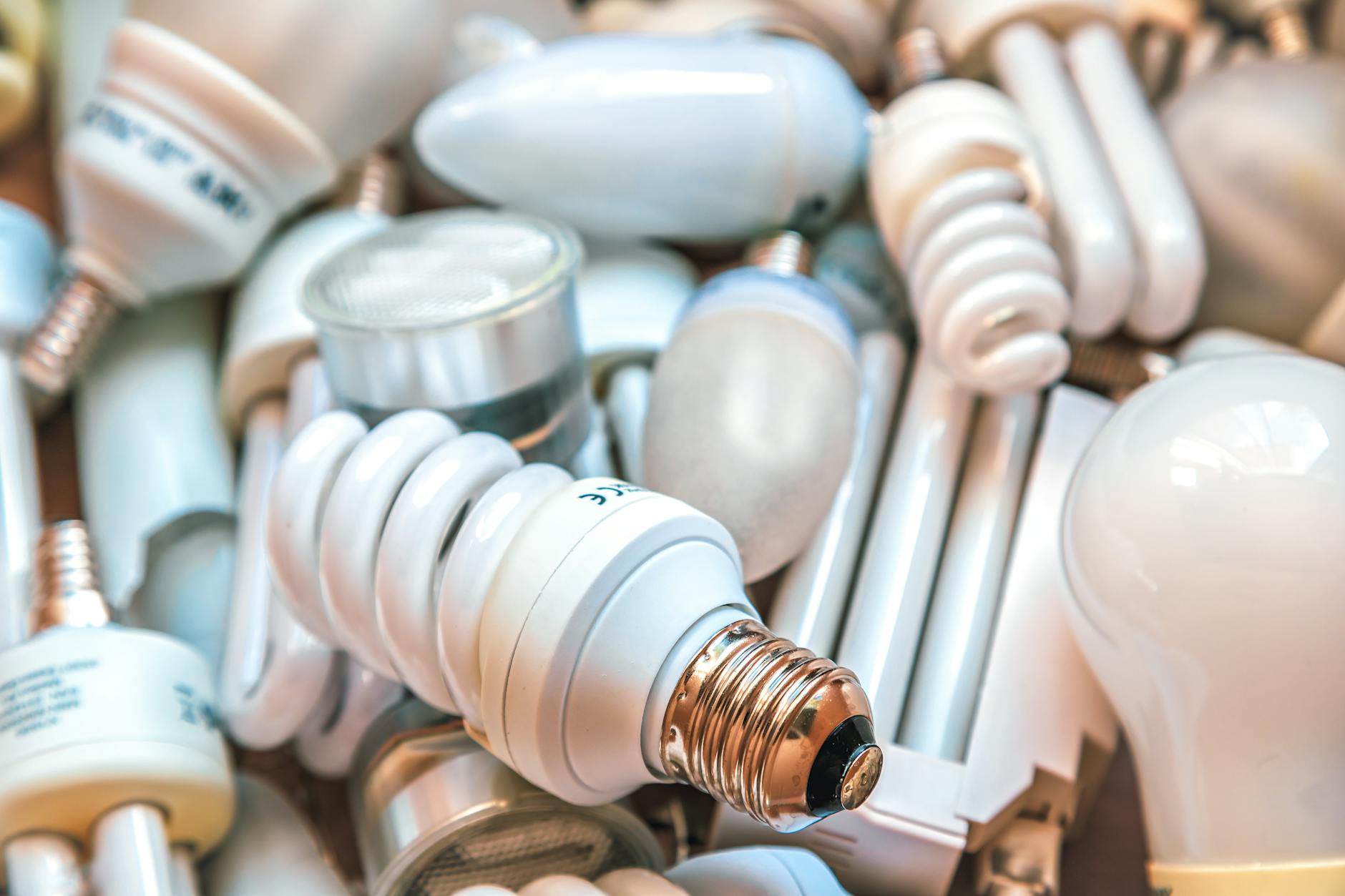 Pile of mixed energy-saving CFL and traditional light bulbs on a surface