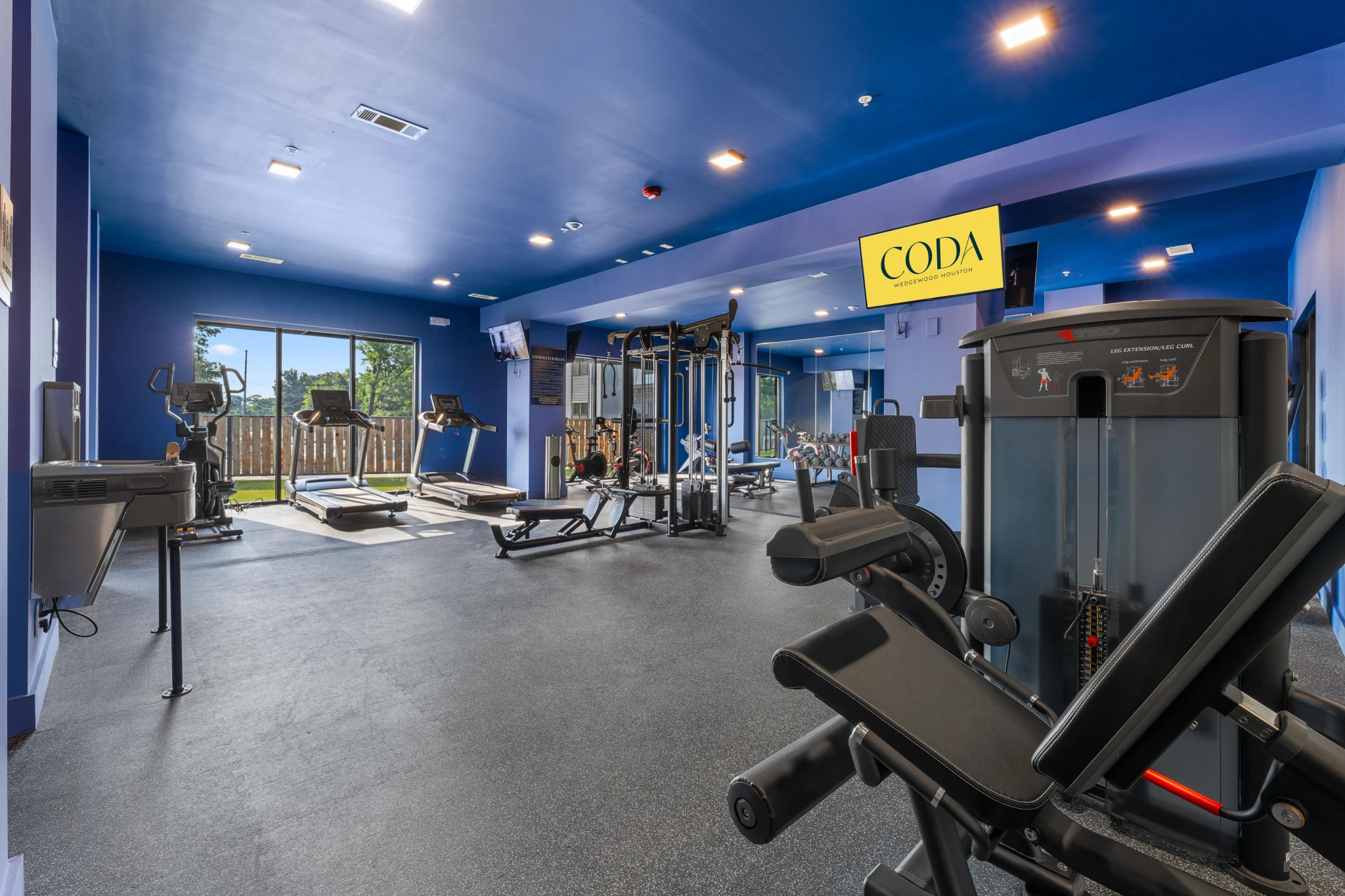 A gym room featuring blue walls and various fitness equipment arranged for workouts.