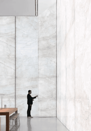 A large wall of white marble with subtle natural veins, offering an elegant and spacious look in a high-ceiling room.