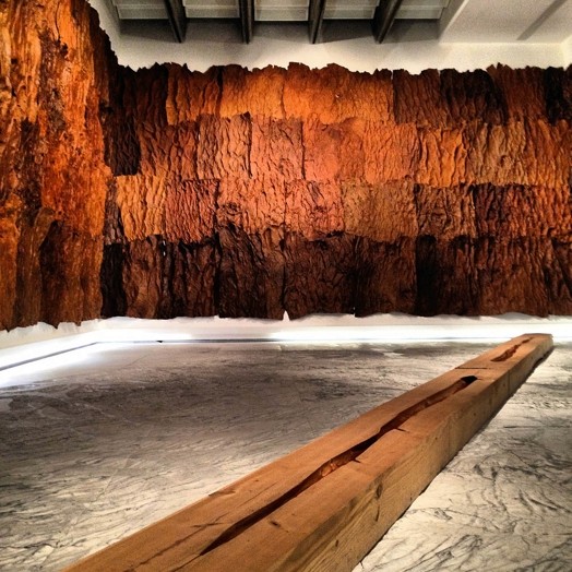 exhibition with fabric on walls and wooden block in the middle