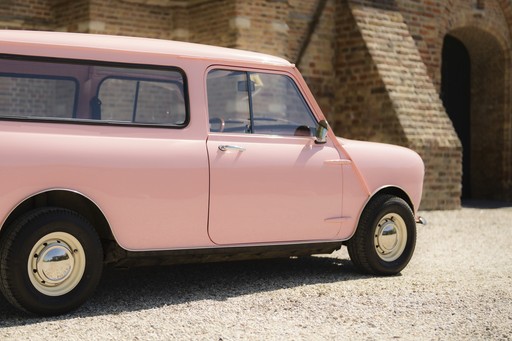 Een klassieke roze bolide geparkeerd bij een stenen muur, pronkend met zijn vintage design en charme.