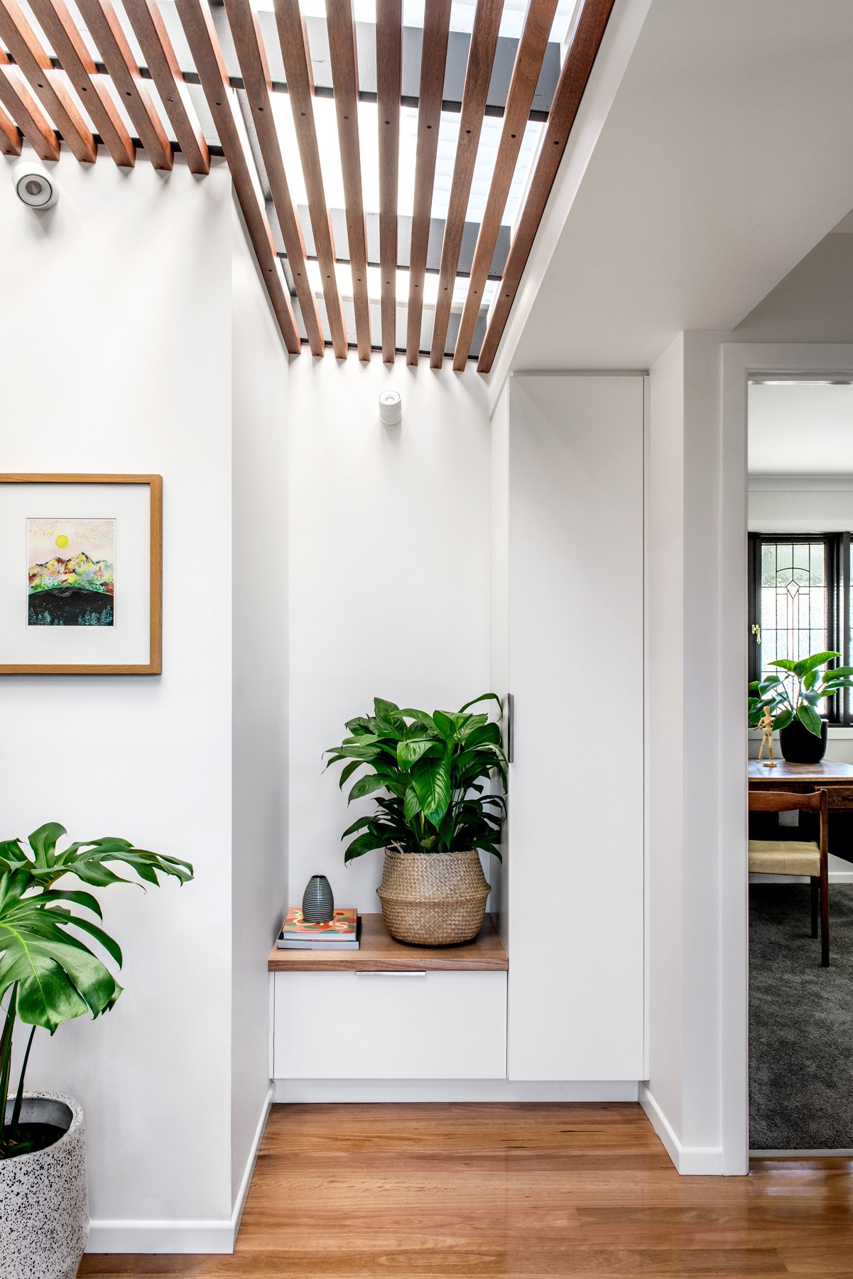 Entry transition at Oxford Cottage with a slatted timber ceiling, built-in bench seating, and integrated planting softening the circulation space.
