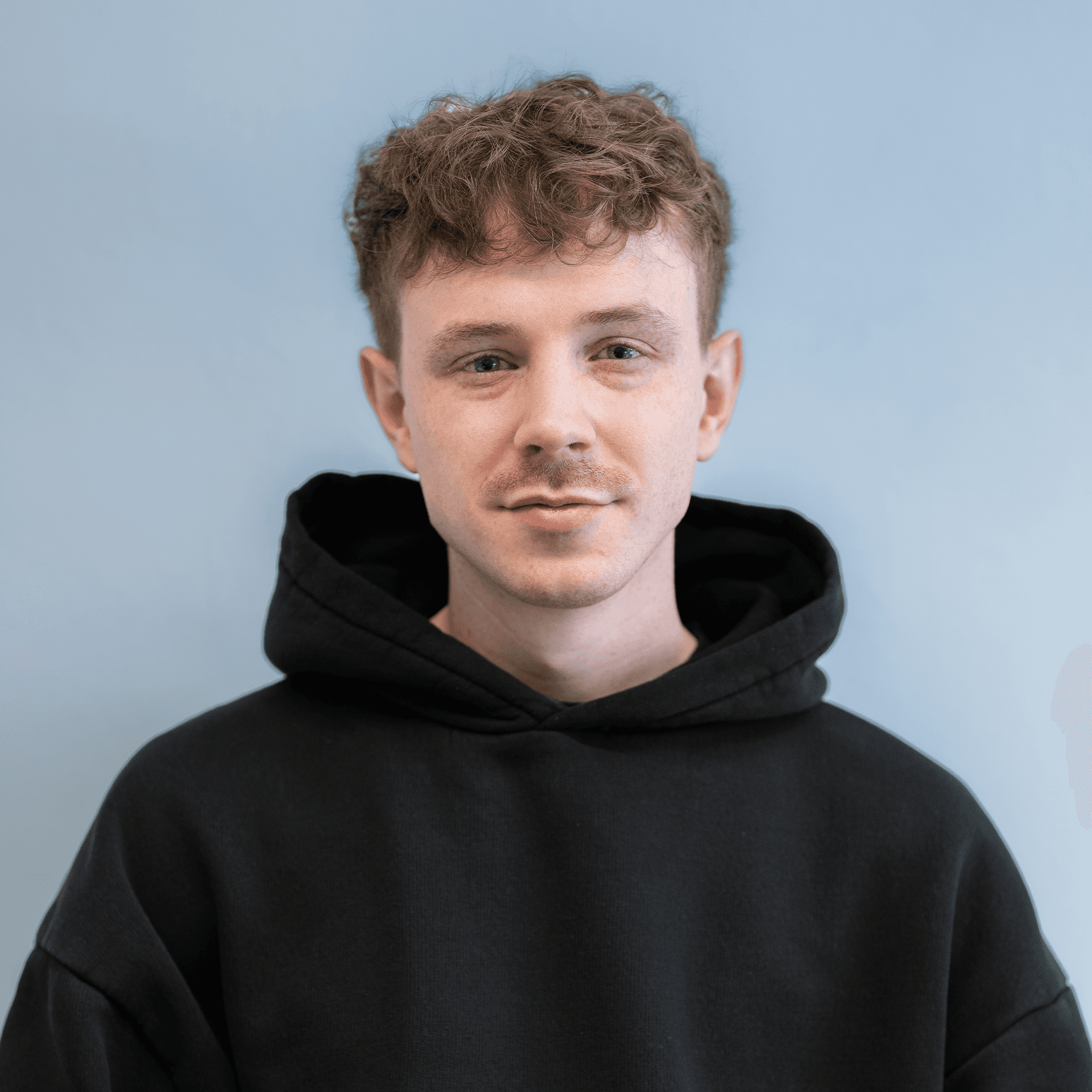 Portrait of a laughing person with curly hair wearing a white shirt