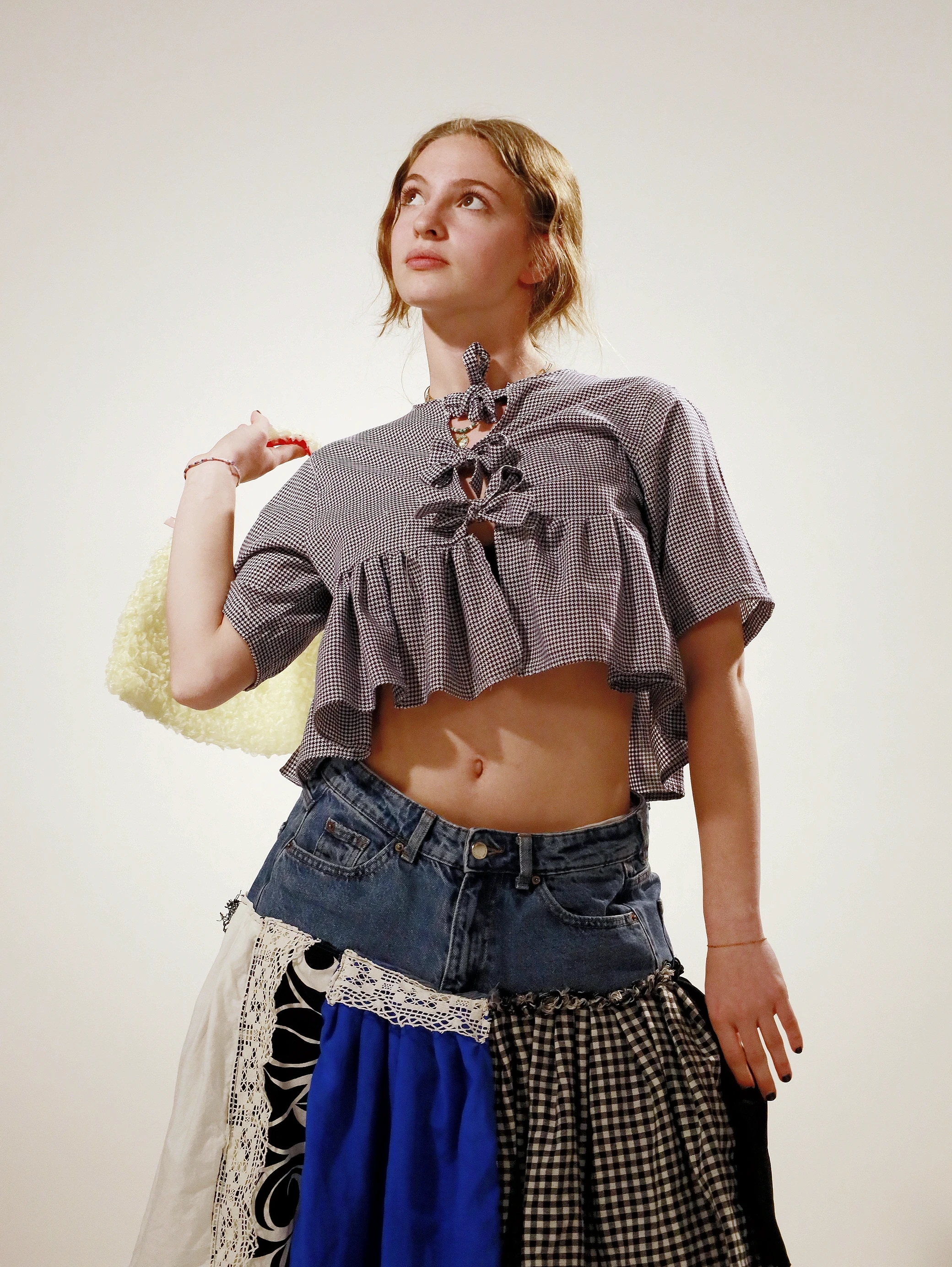 A model poses confidently in a cropped gray top and a colorful, layered skirt against a plain background.