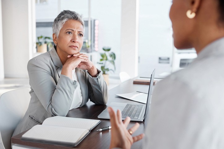 Middle age professional woman listens to another professional woman talking