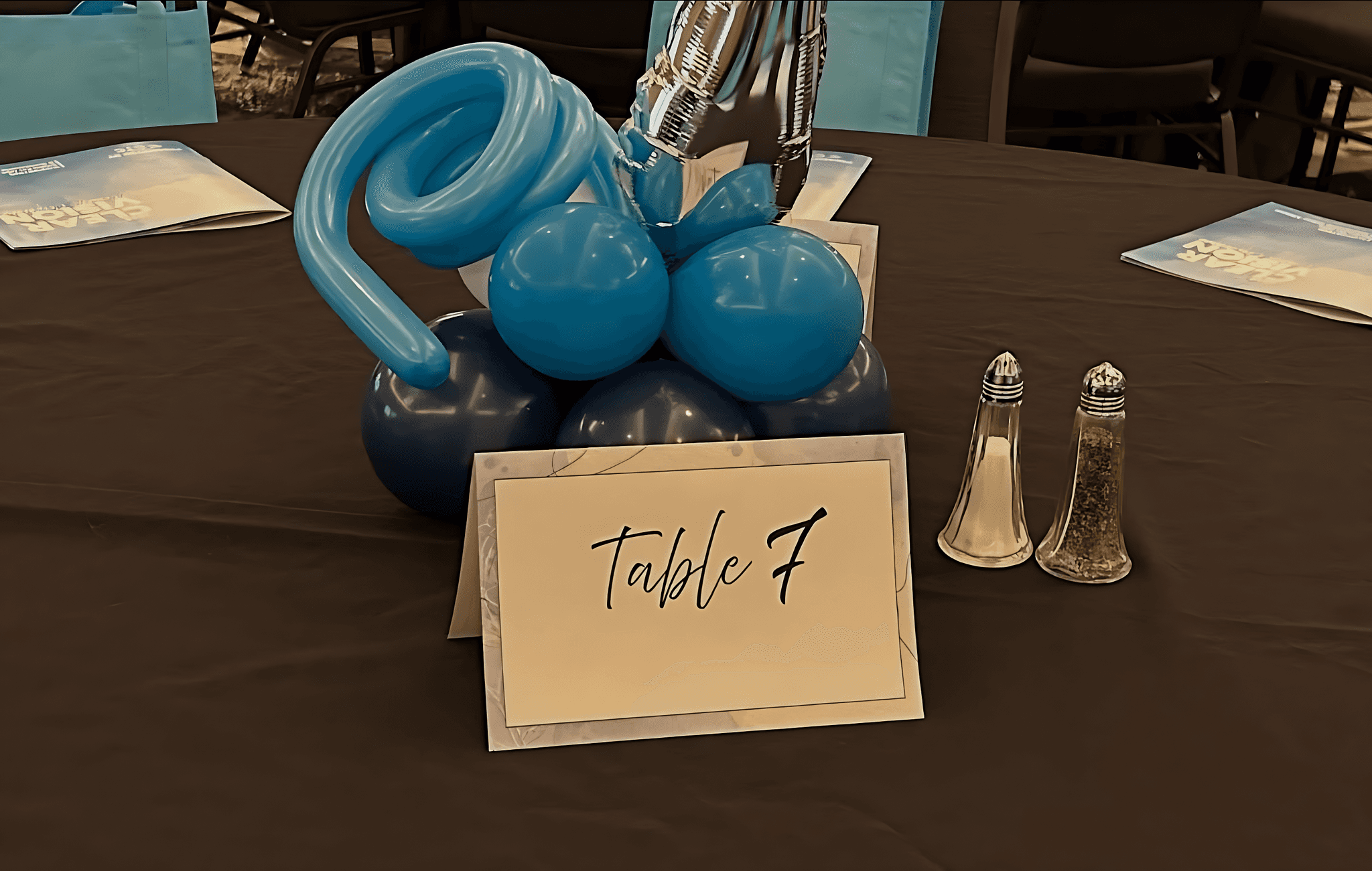 Blue balloon arrangement with a white tabletop sign that says Table 7 set for an event by Be Bold Balloons