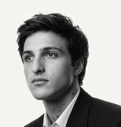 A professional black-and-white headshot of Philip Heyes in formal attire looking off to the side, conveying a thoughtful expression and neatly styled hair against a plain background.