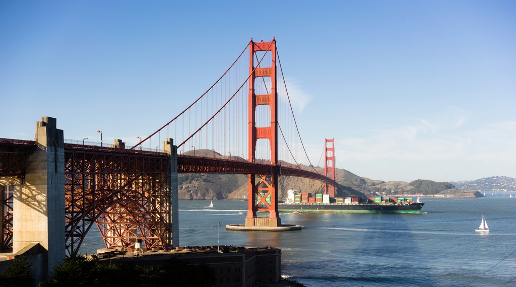 Side view of the San Francisco Golden Gate bridge against blue sky.