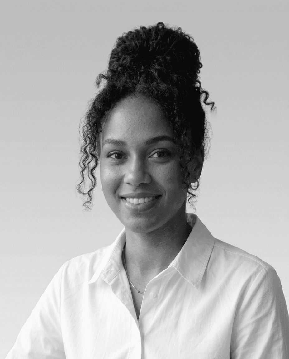 Close-up portrait of a freckled woman with soft pink hair and star earring, natural light, white tank top.