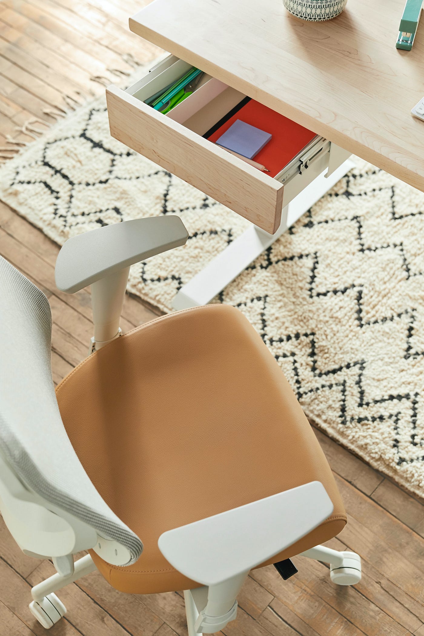 An office chair by a desk with a pulled-out drawer.