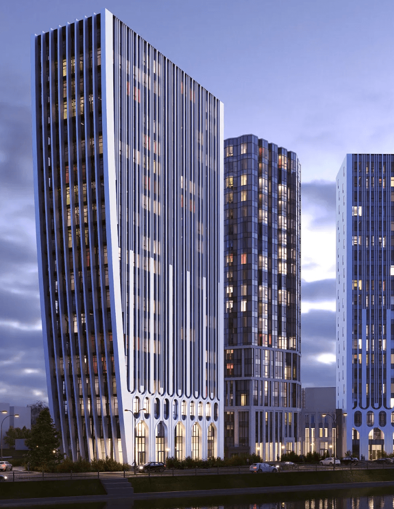 A smiling woman with her arms crossed, standing against a dark green background. She has long, dark hair.