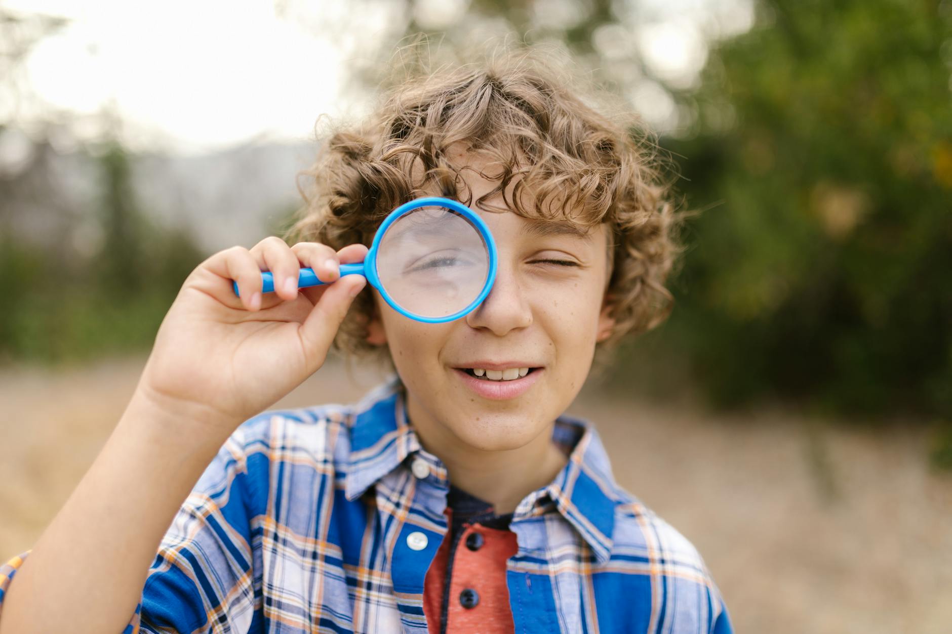 A curious student looking through a microscope in a science lab while recording observations in a journal.