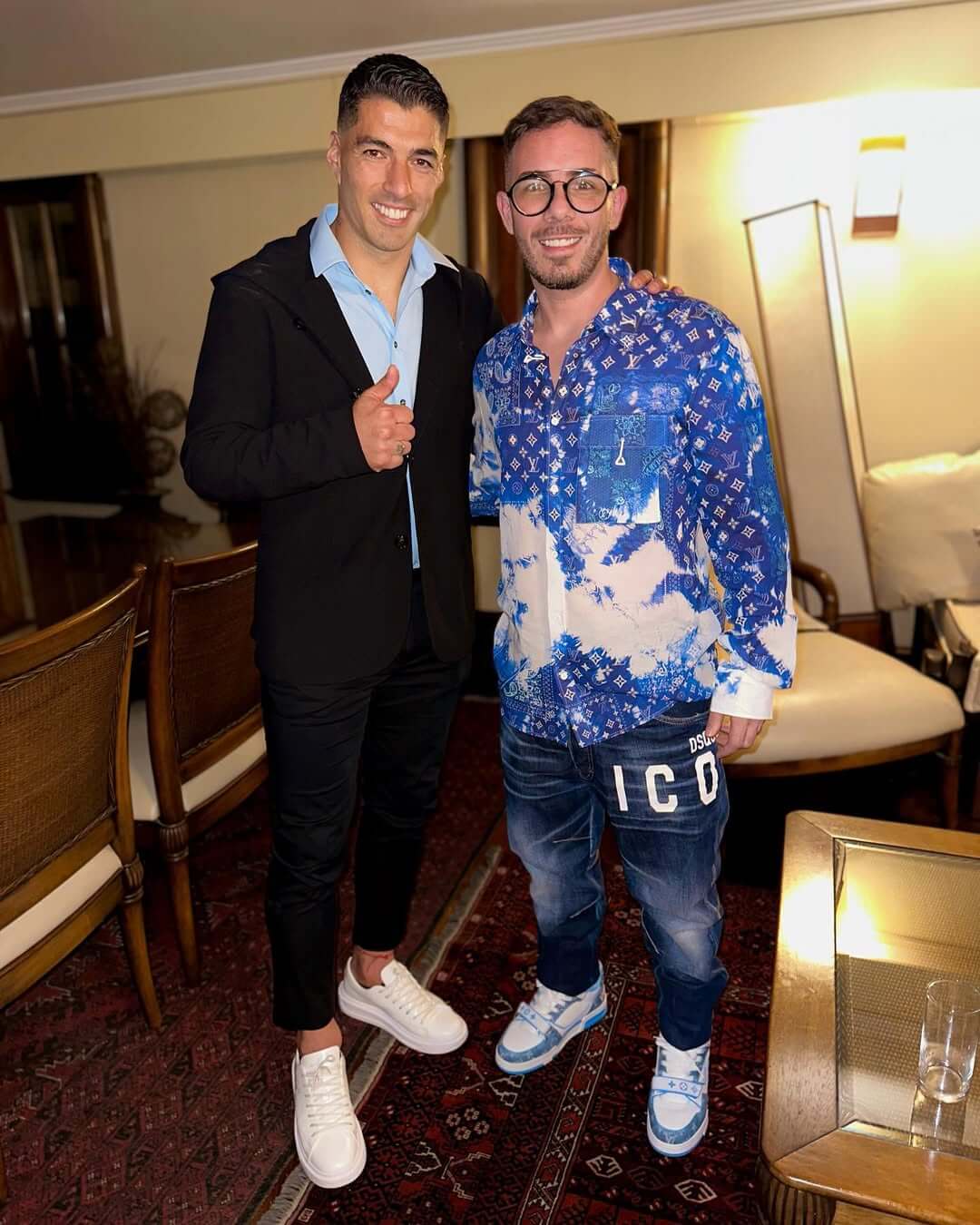 Fer Palacio junto a Luis Suárez, ambos posando con atuendos elegantes.