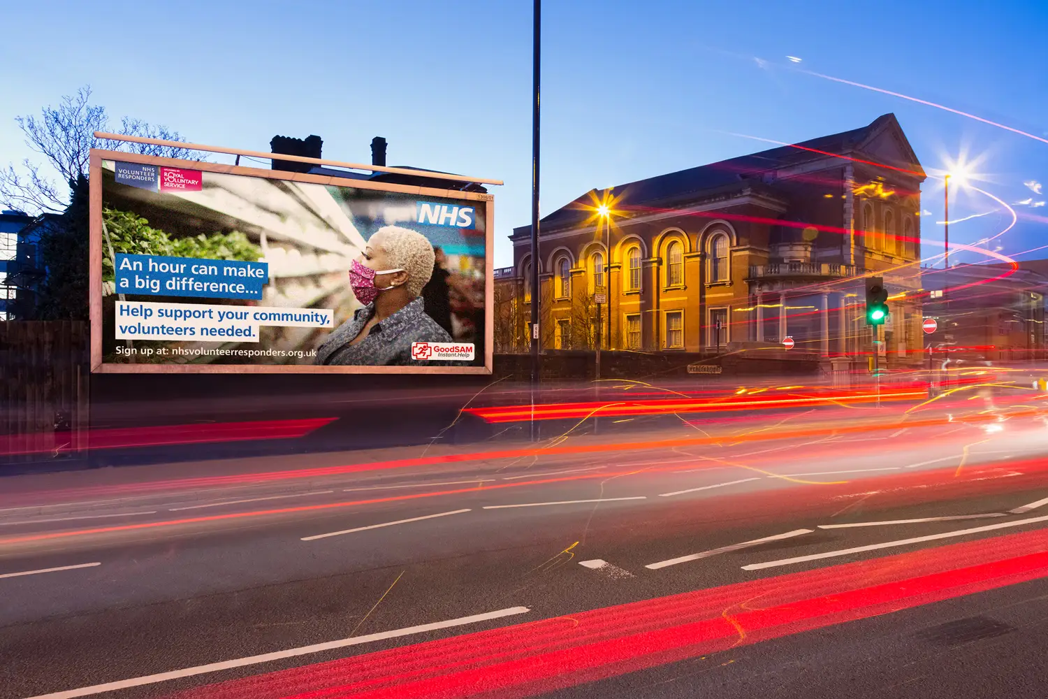 NHS Volunteer Responders billboard at night calling for volunteers with Royal Voluntary Service partnership logo
