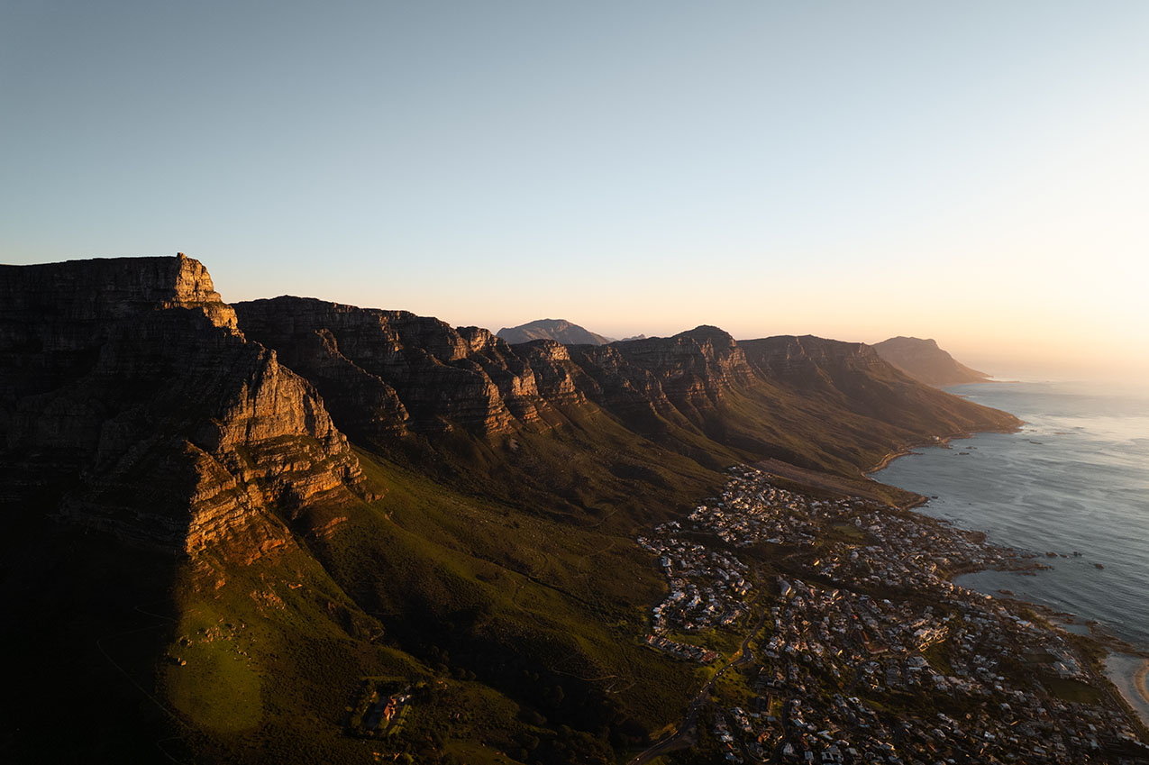 Drone view of Table Mountain at sunset with the city and ocean in Cape Town, South Africa.