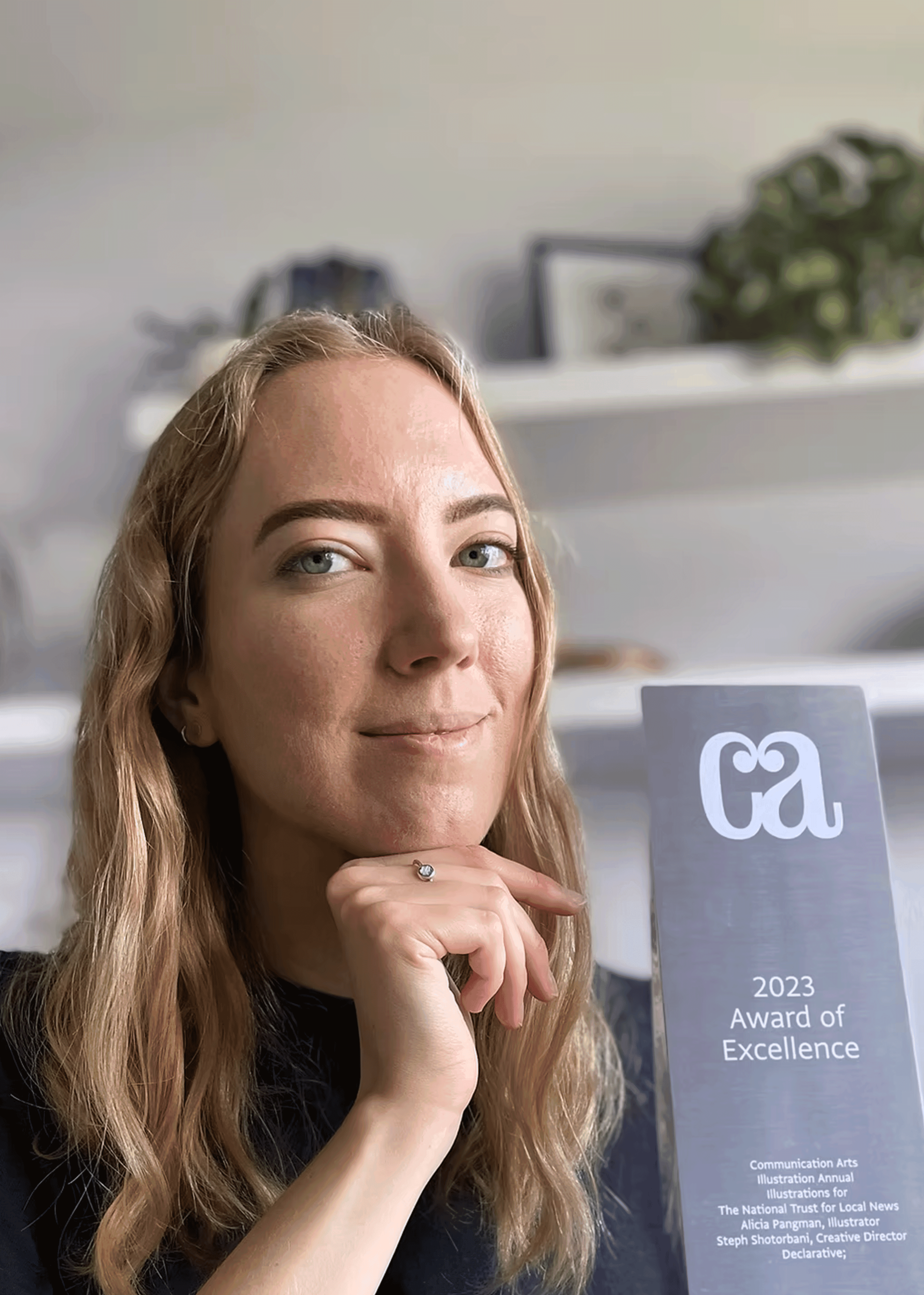 Declarative creative consultancy team member holding the 2023 Communication Arts Award of Excellence for design.