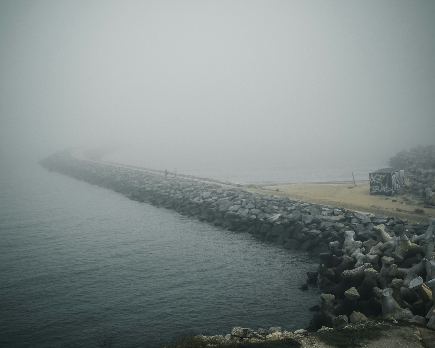 A stone pier disappearing into sea fog