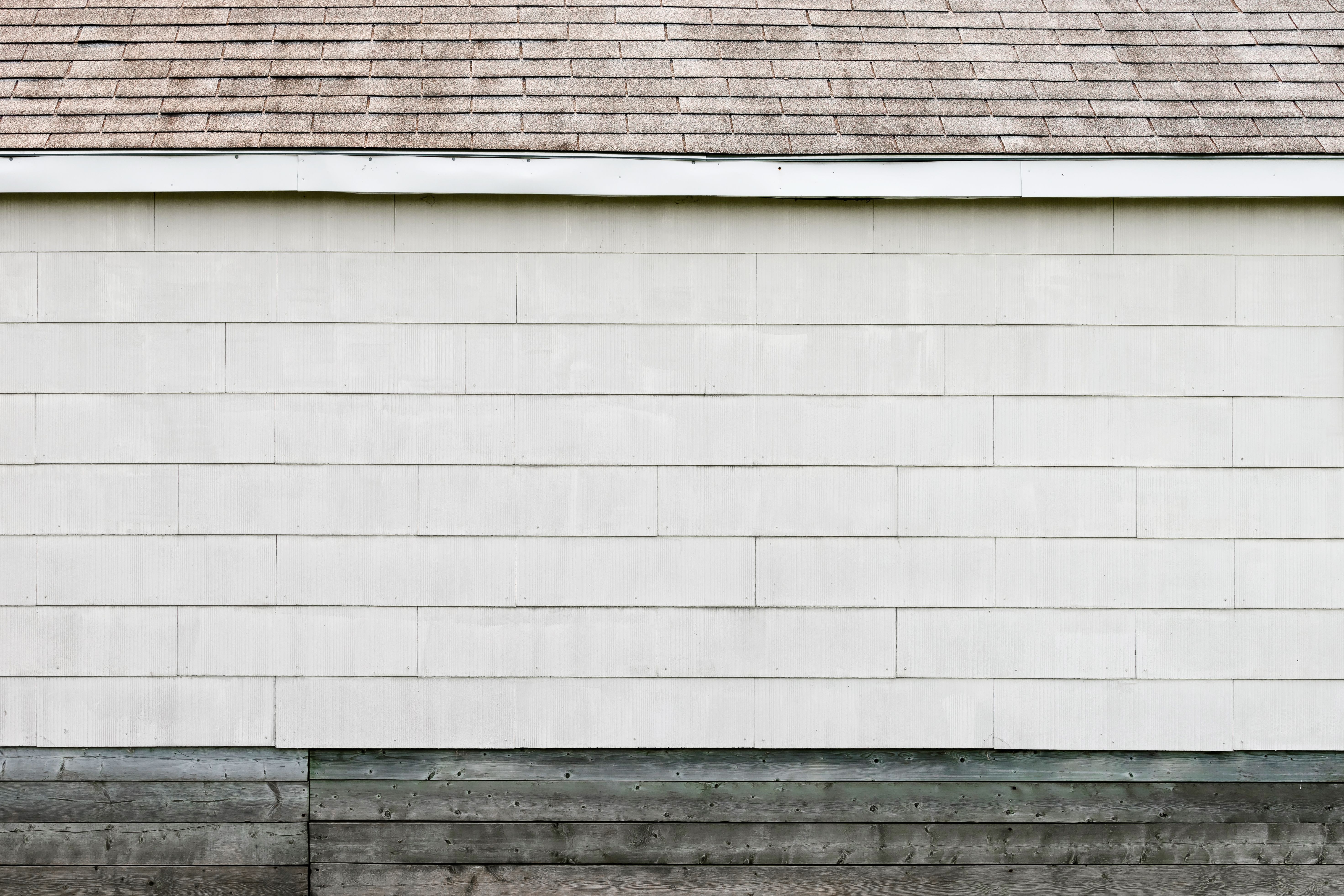White siding and shingled roof detail on a home exterior