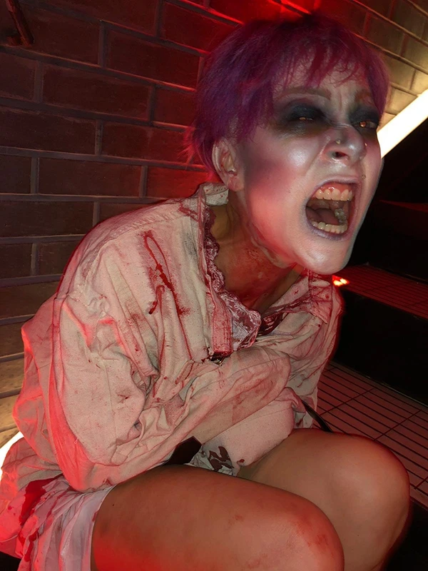 Zombie patient performer in a bloody hospital gown