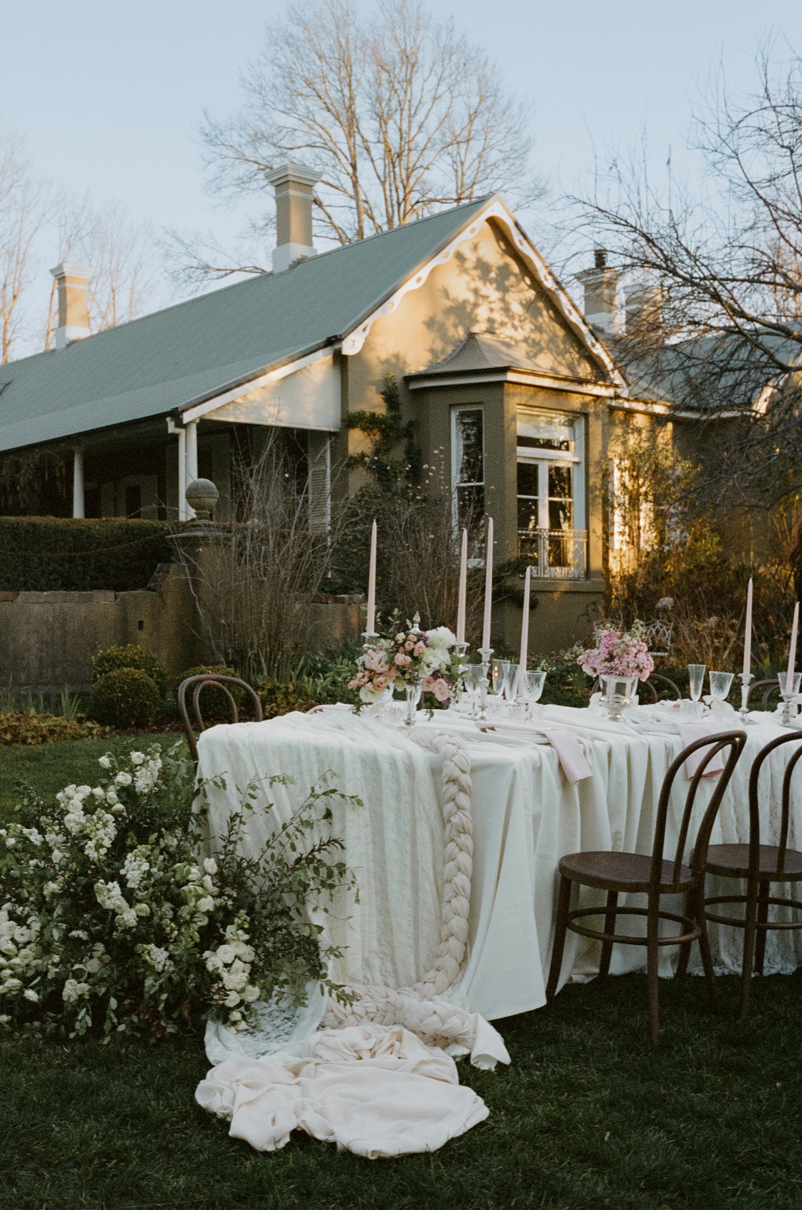Long outdoor reception table styled beside a historic Mona Farm building