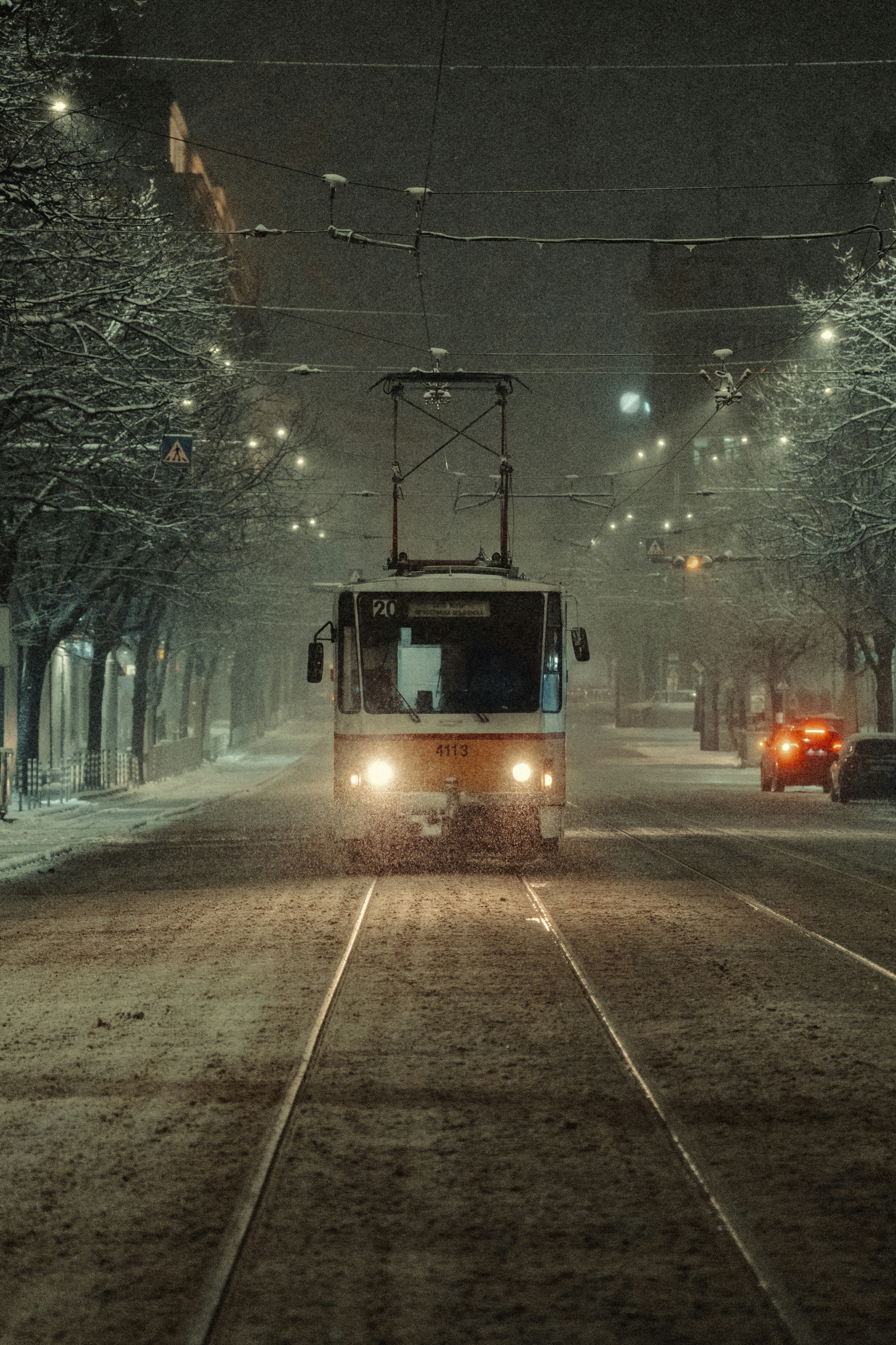 Tram driving on a snowy street at night