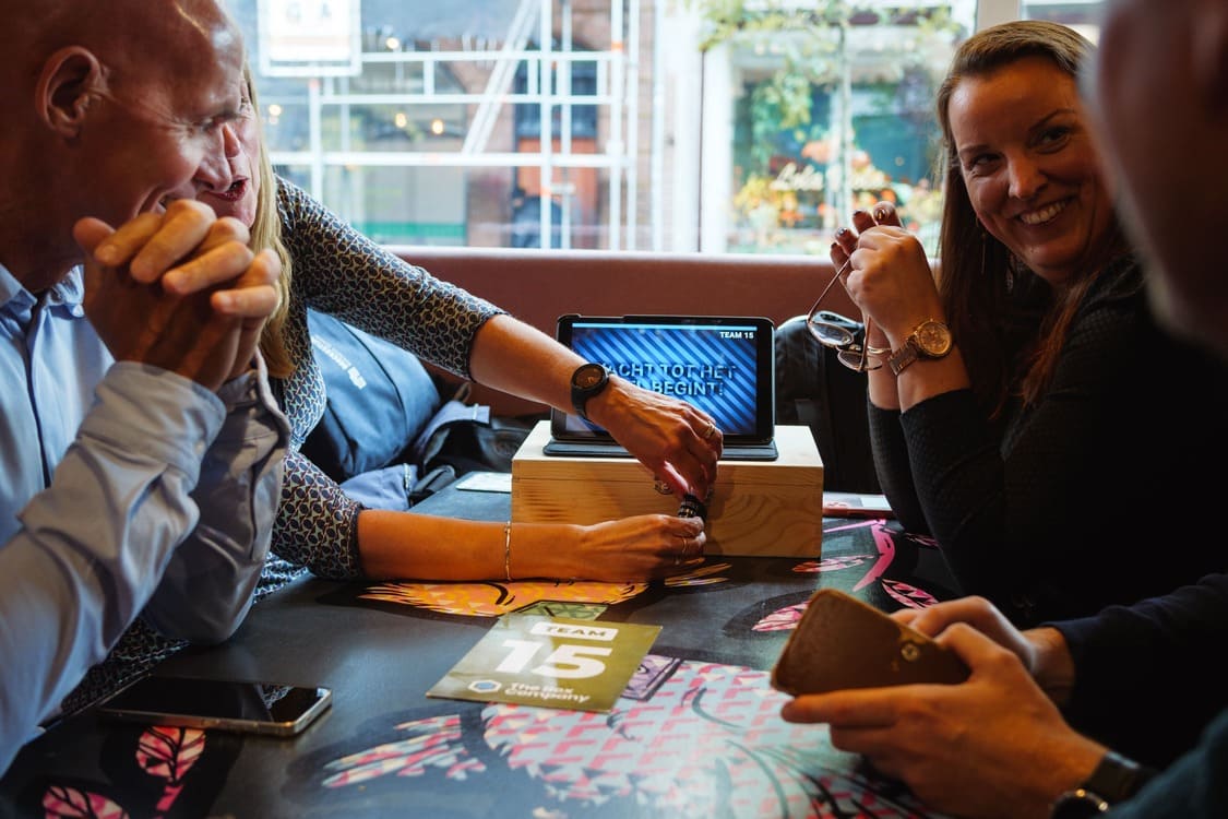 Deelnemers lossen een puzzel op en openen een cijferslot aan een kist tijdens een teambuildingactiviteit van The Box Company.