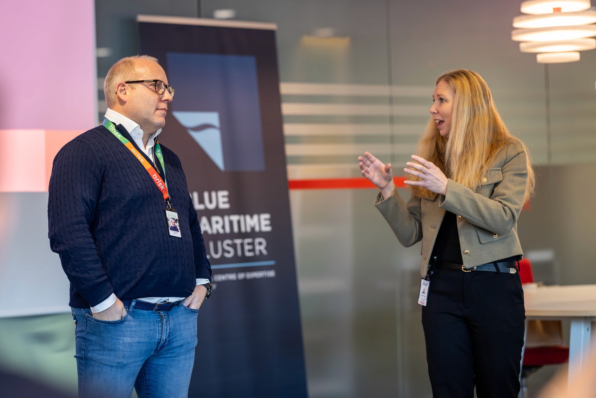 A group of people mingling at an event, with one man looking upwards, appearing deep in thought.