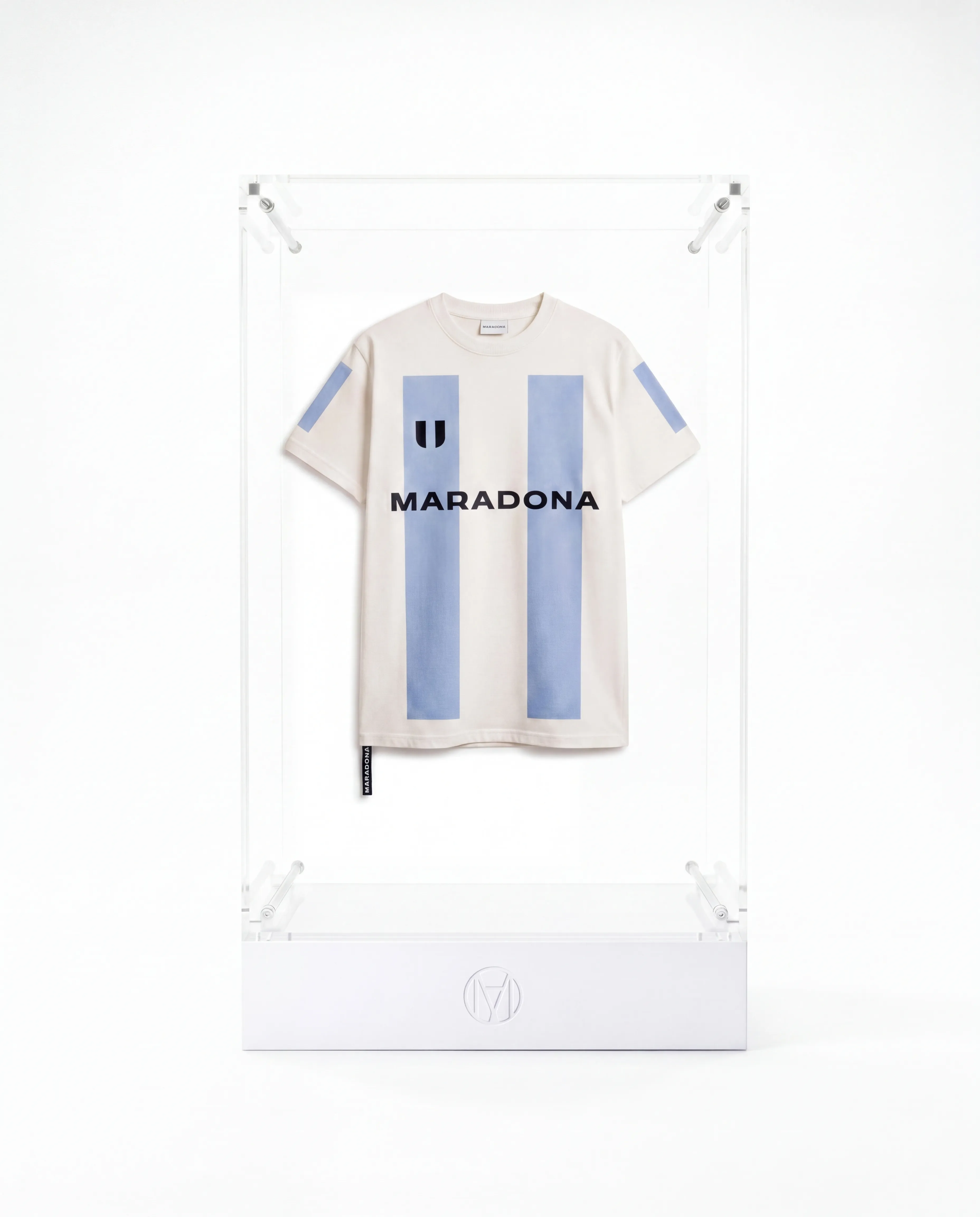 Maradona Official cream t-shirt with blue vertical stripes and logo, displayed inside a clear acrylic display case on a branded white branded plinth