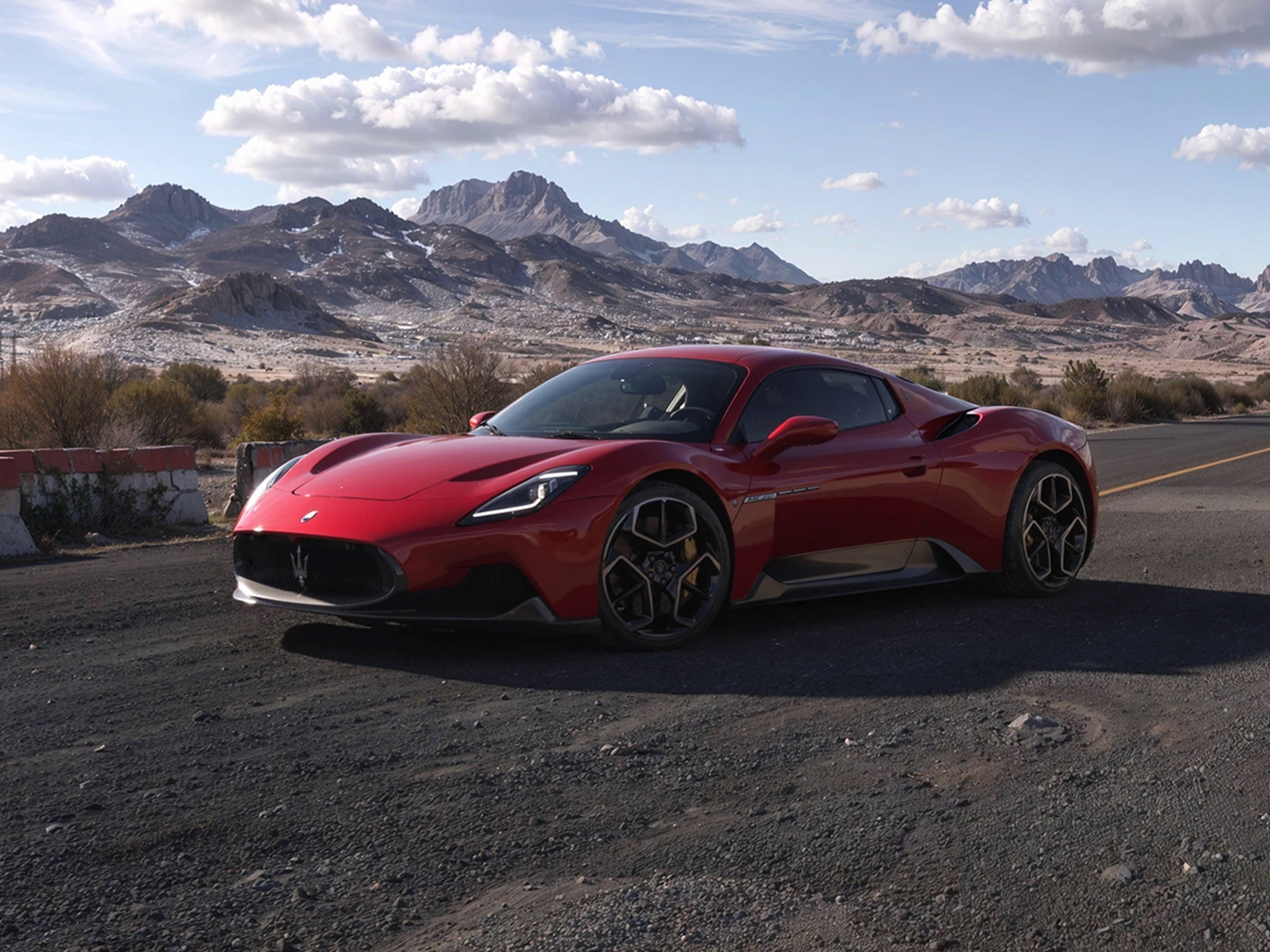 Maserati MC20 coupé colore rosso con cerchi in lega scuri, vista frontale e laterale in ambientazione montana.