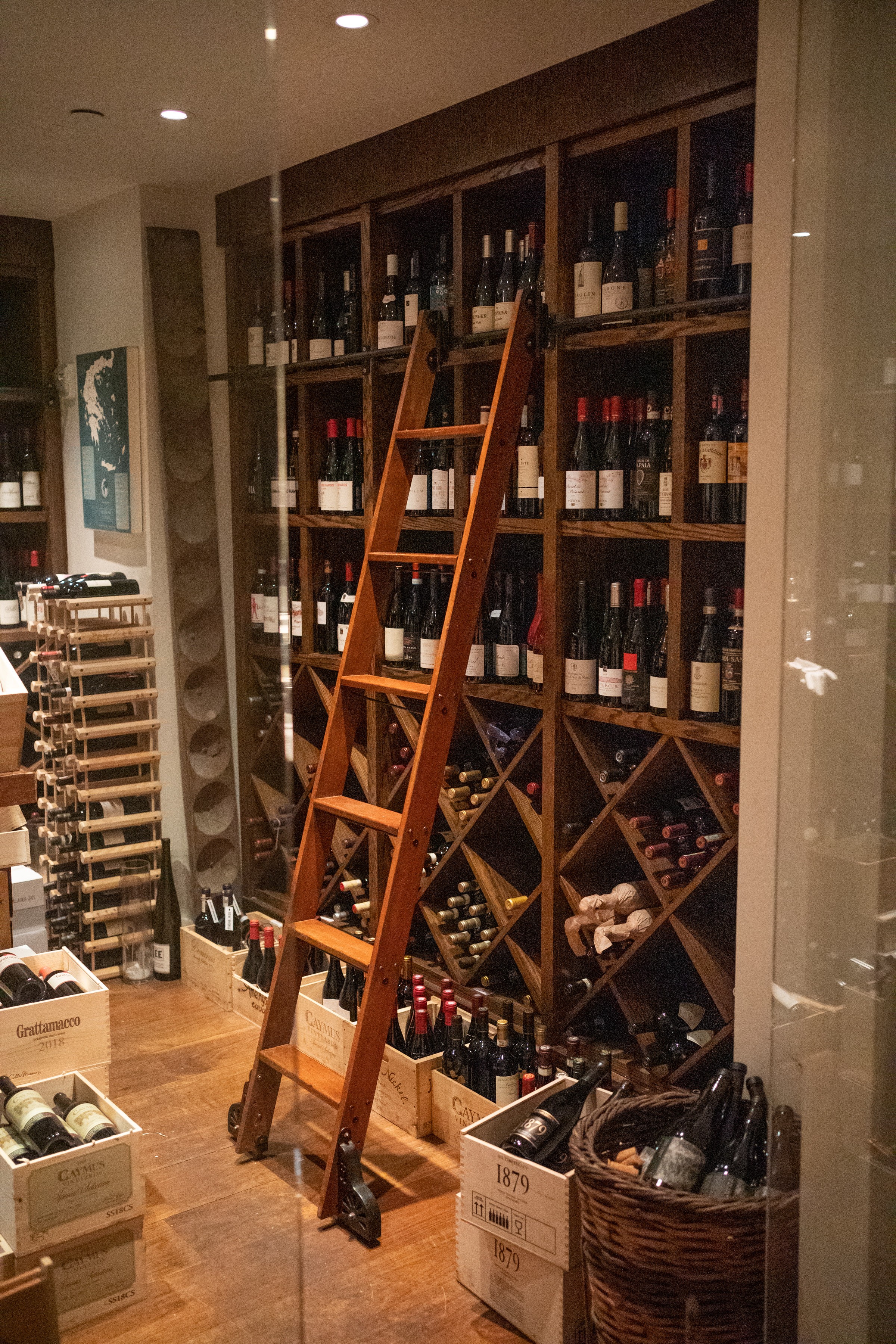 A neatly organized wine rack displaying various bottles in a cozy, warmly lit setting.