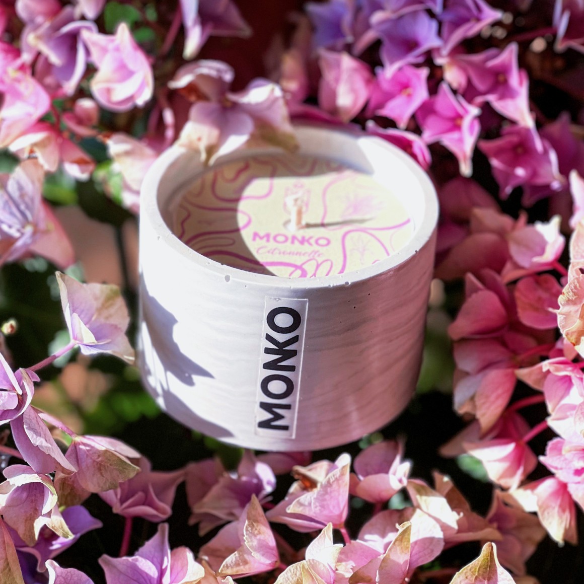 Photo d'une bougie artisanale sur des fleurs roses violacées.