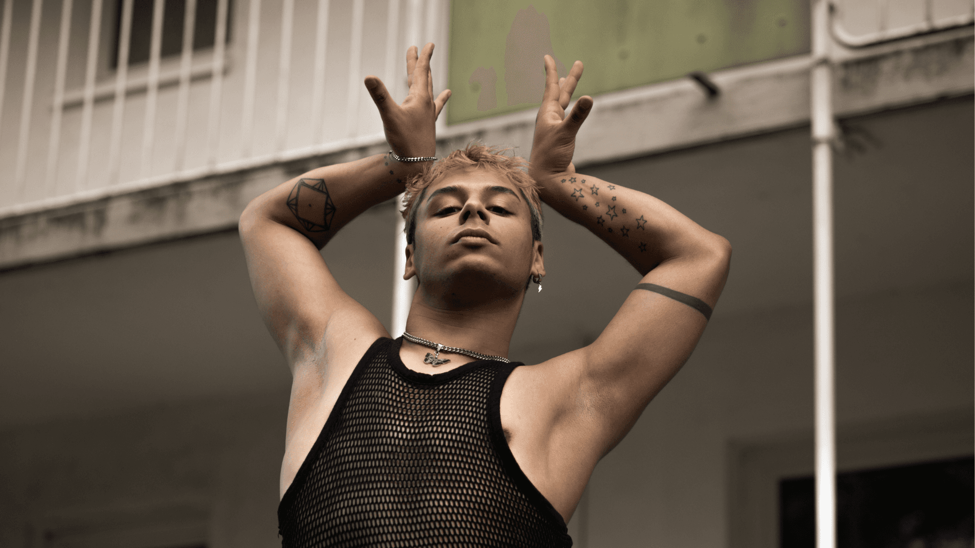 A person with arms raised and fingers resembling antlers, striking a dynamic pose against a blurred background.