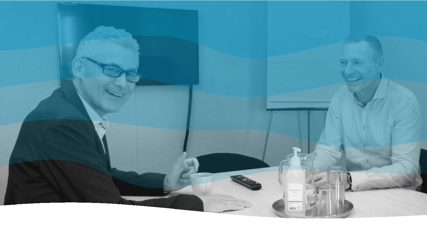 Twee mannen in een vergaderruimte op kantoor glimlachen