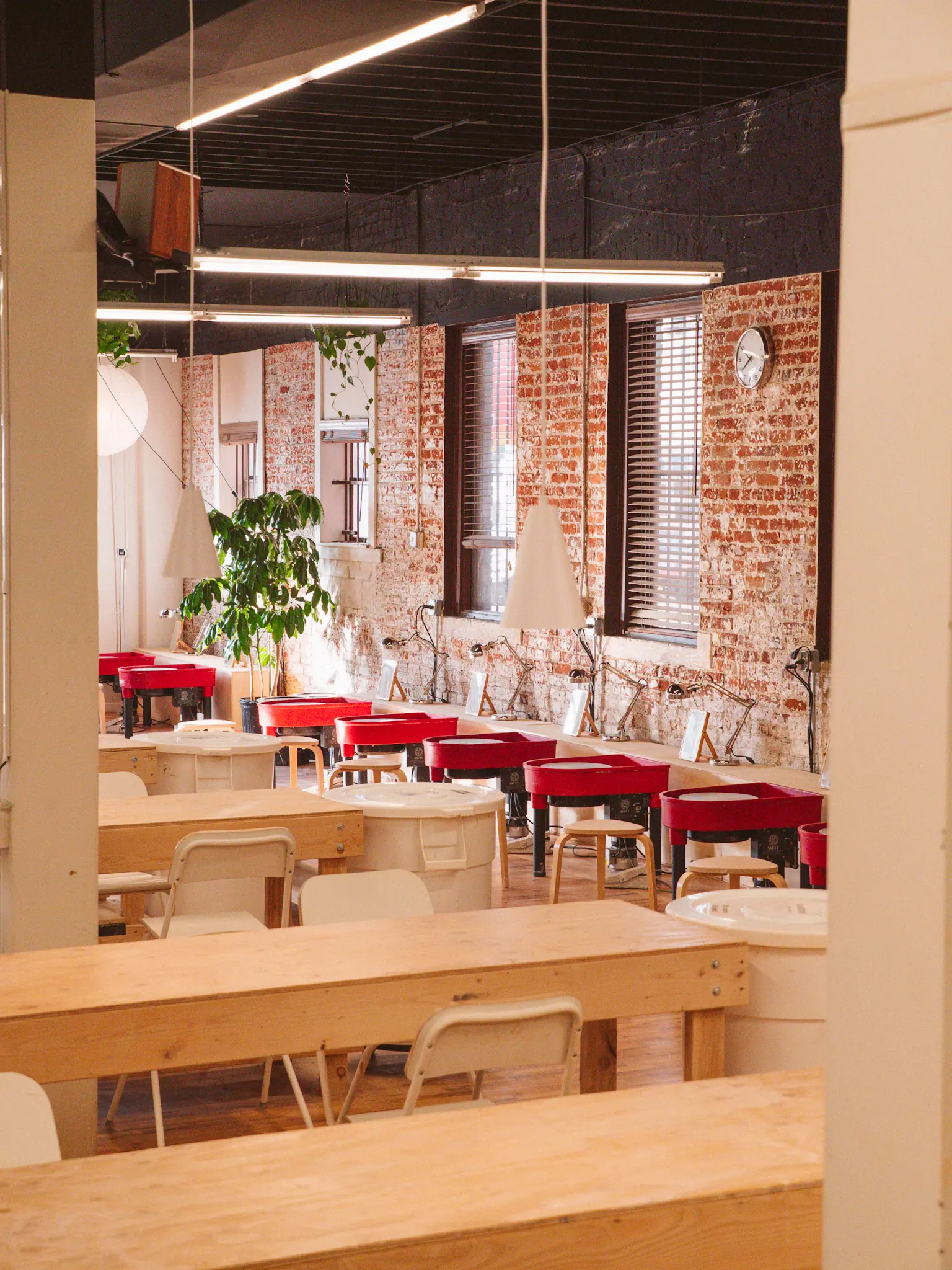 Row of red pottery wheels along the brick wall inside Kinship, a members-only pottery studio in Denver