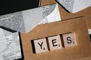 Letter tiles spelling 'YES' on brown paper, illustrating the consensus principle of persuasion