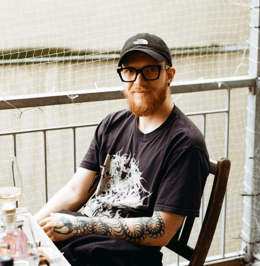 A thoughtful young person with dark hair gazes to the side, captured in soft black and white lighting.